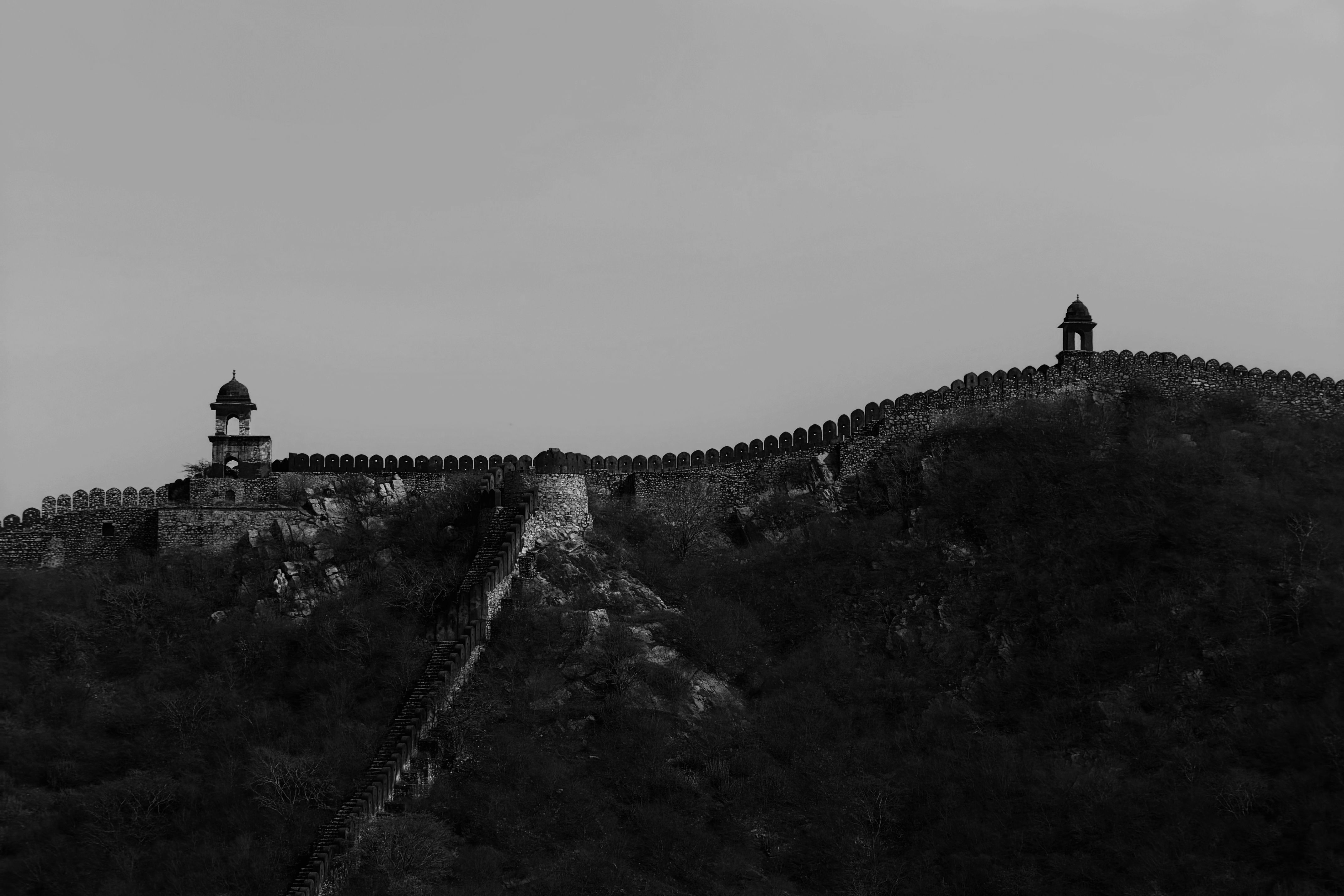 a black and white photograph showcasing the historic jaigarh forts wall extending across a hilltop in jaipur