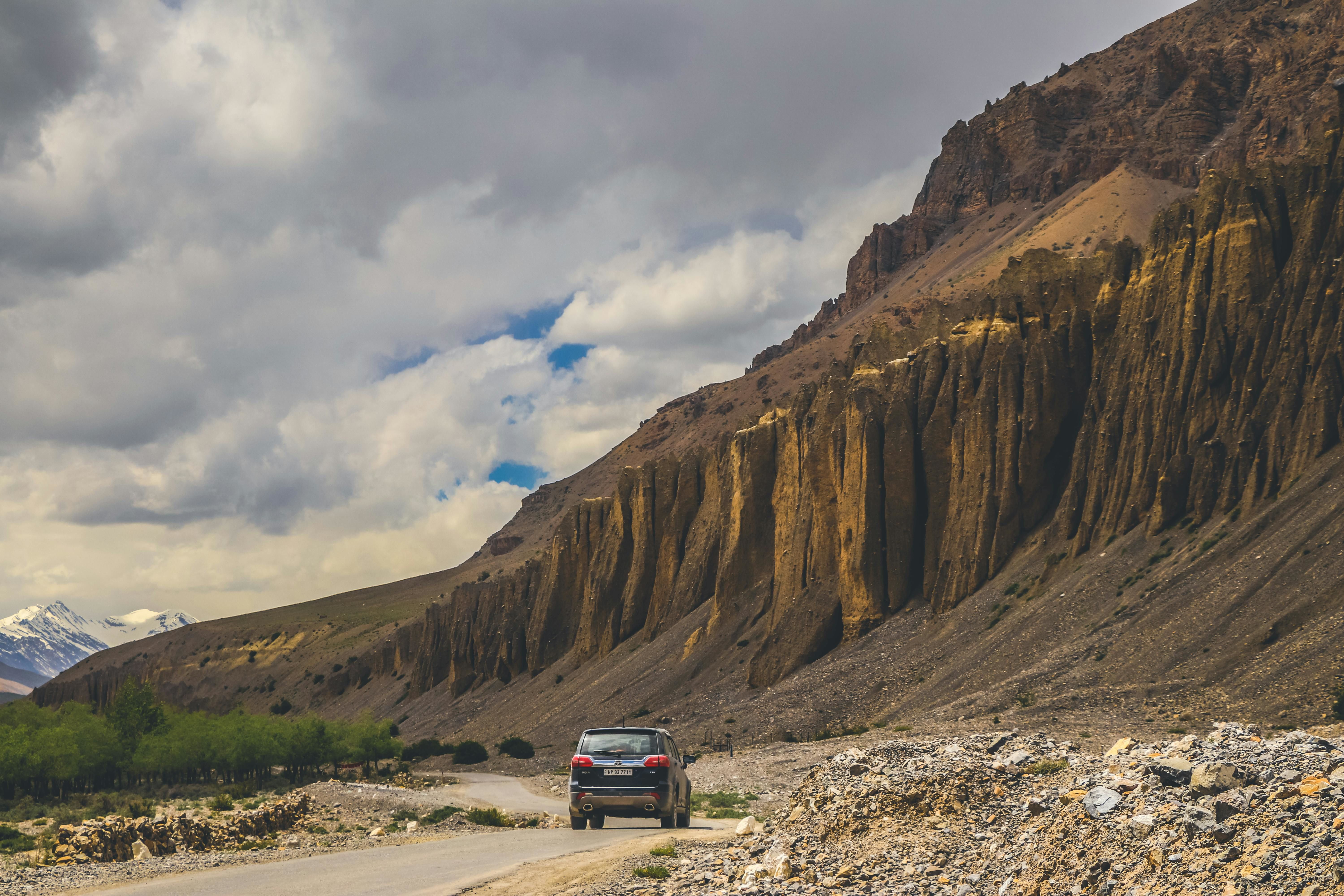 a black car on the road along rocky brown mountains in dhankar