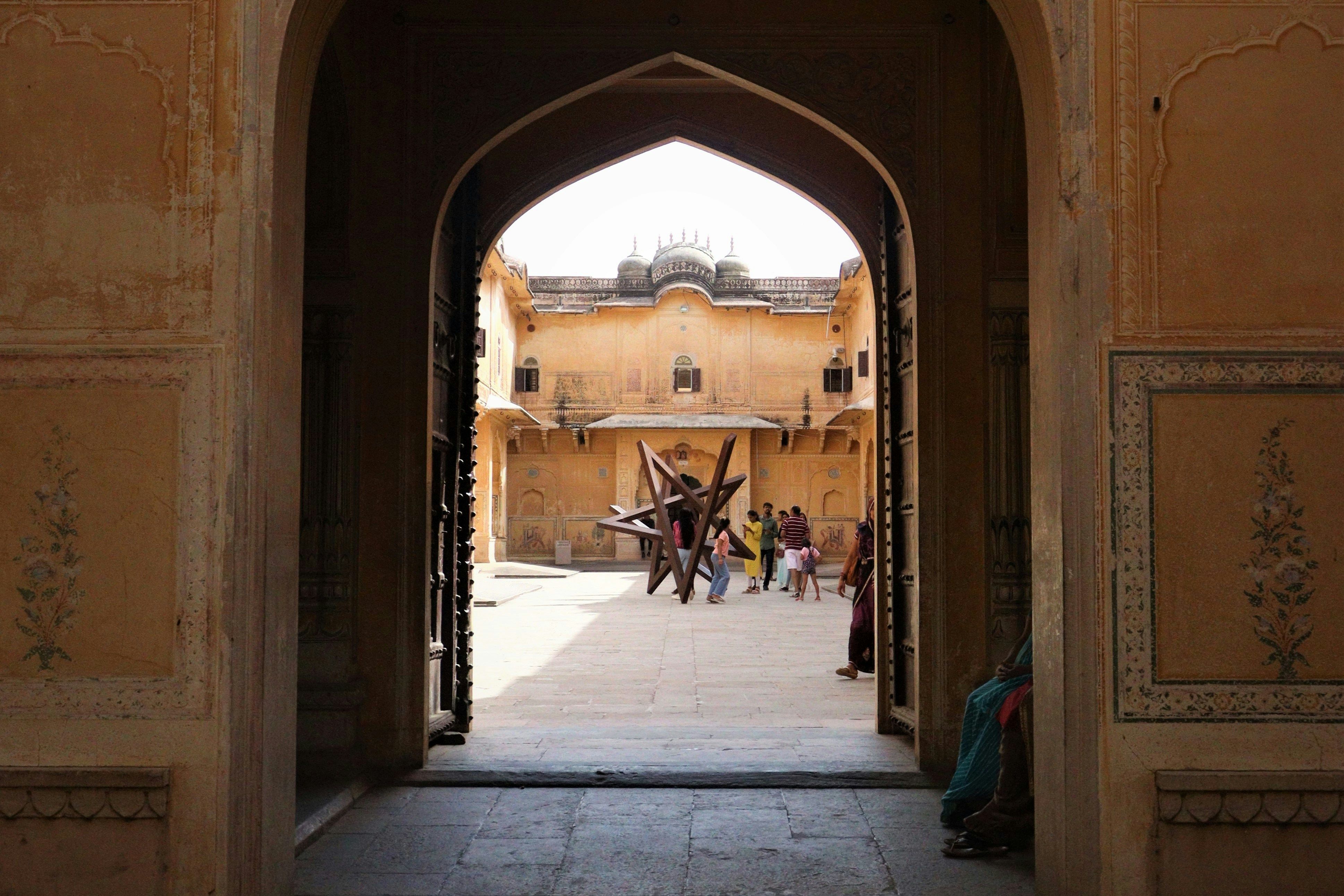 a couple of people sitting on a bench under an archway inside the nahargarh fort