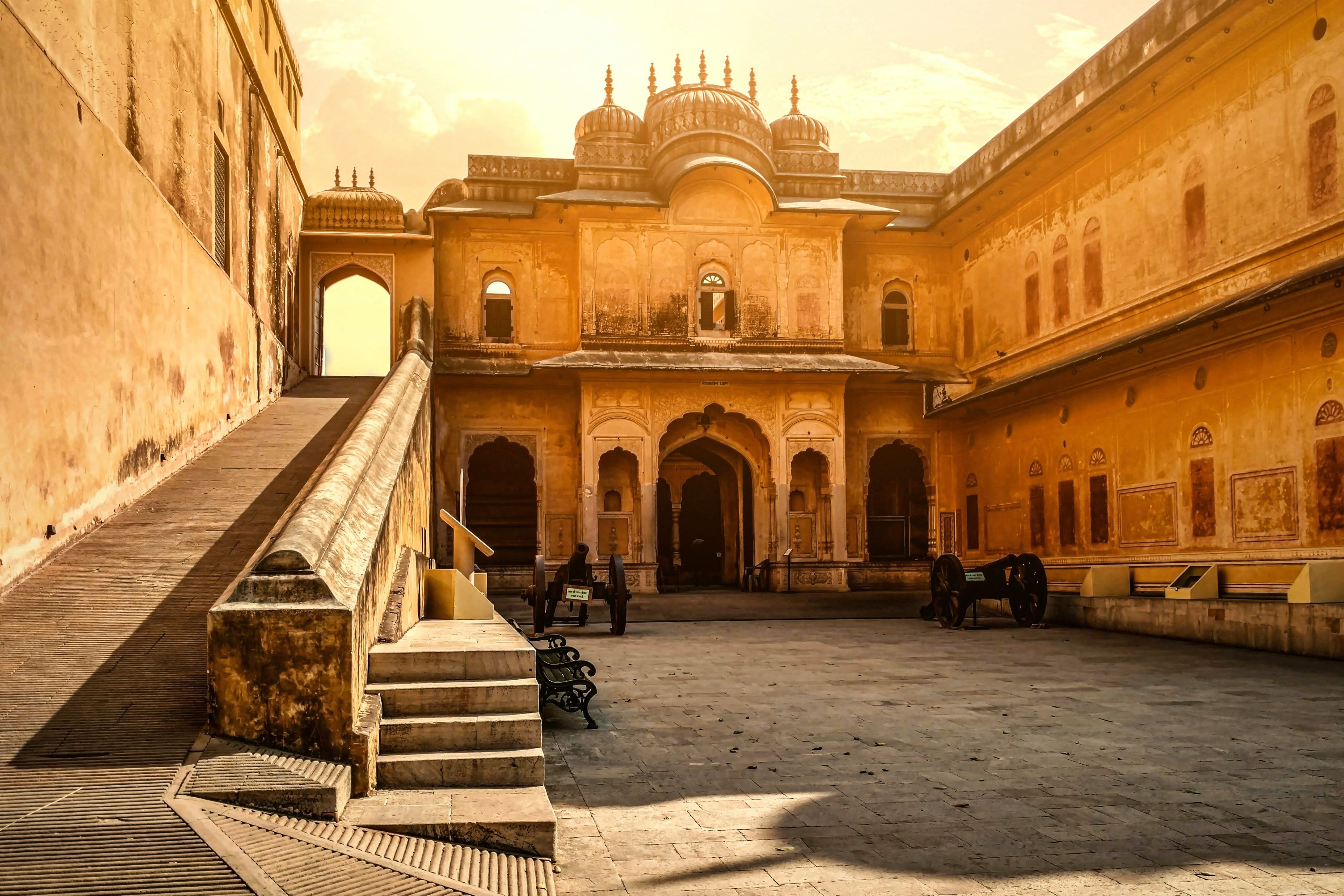 a courtyard with buildings and people with nahargarh fort in the background