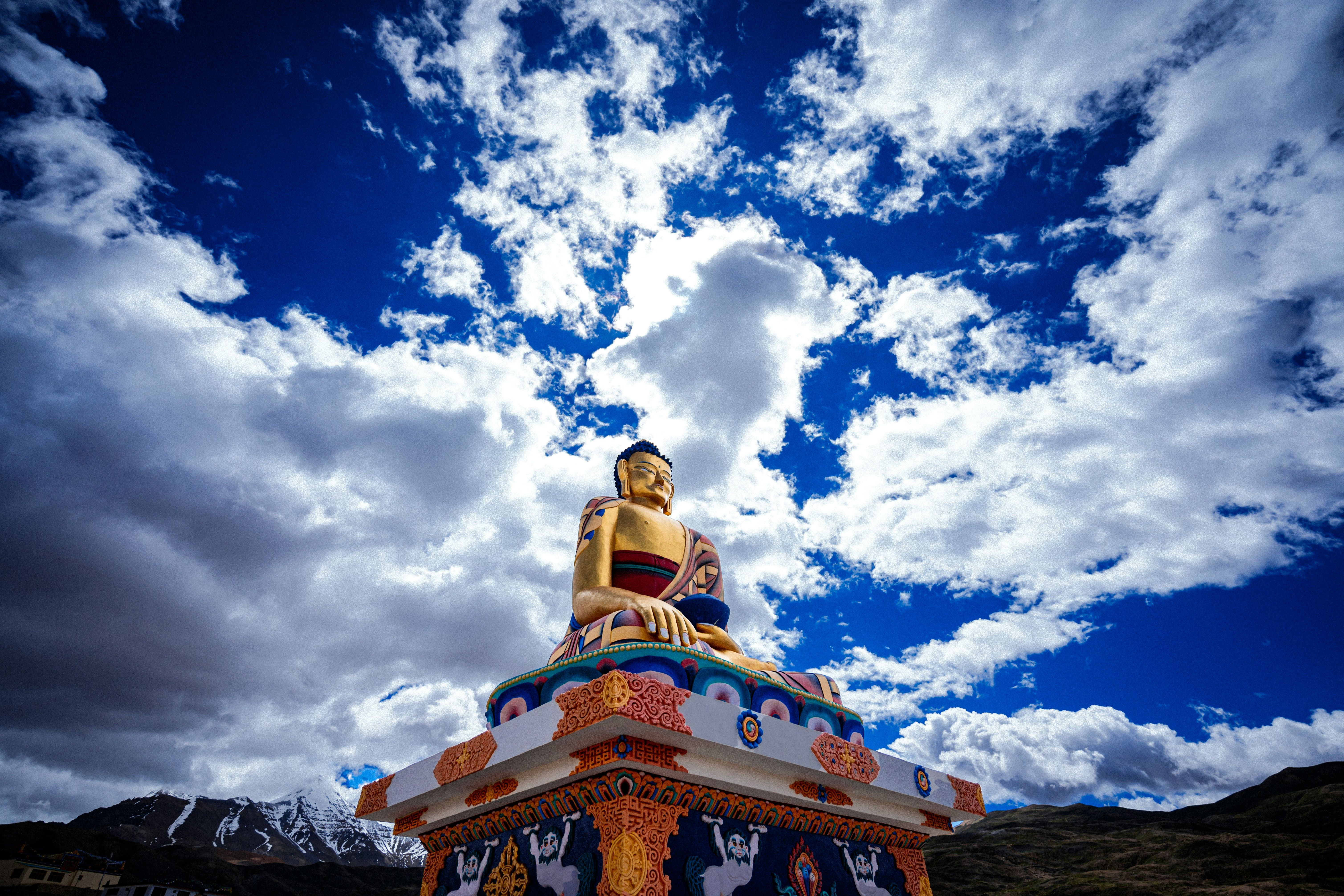 a golden statue of gautam buddha sitting on top of a hill in langza village in spiti valley
