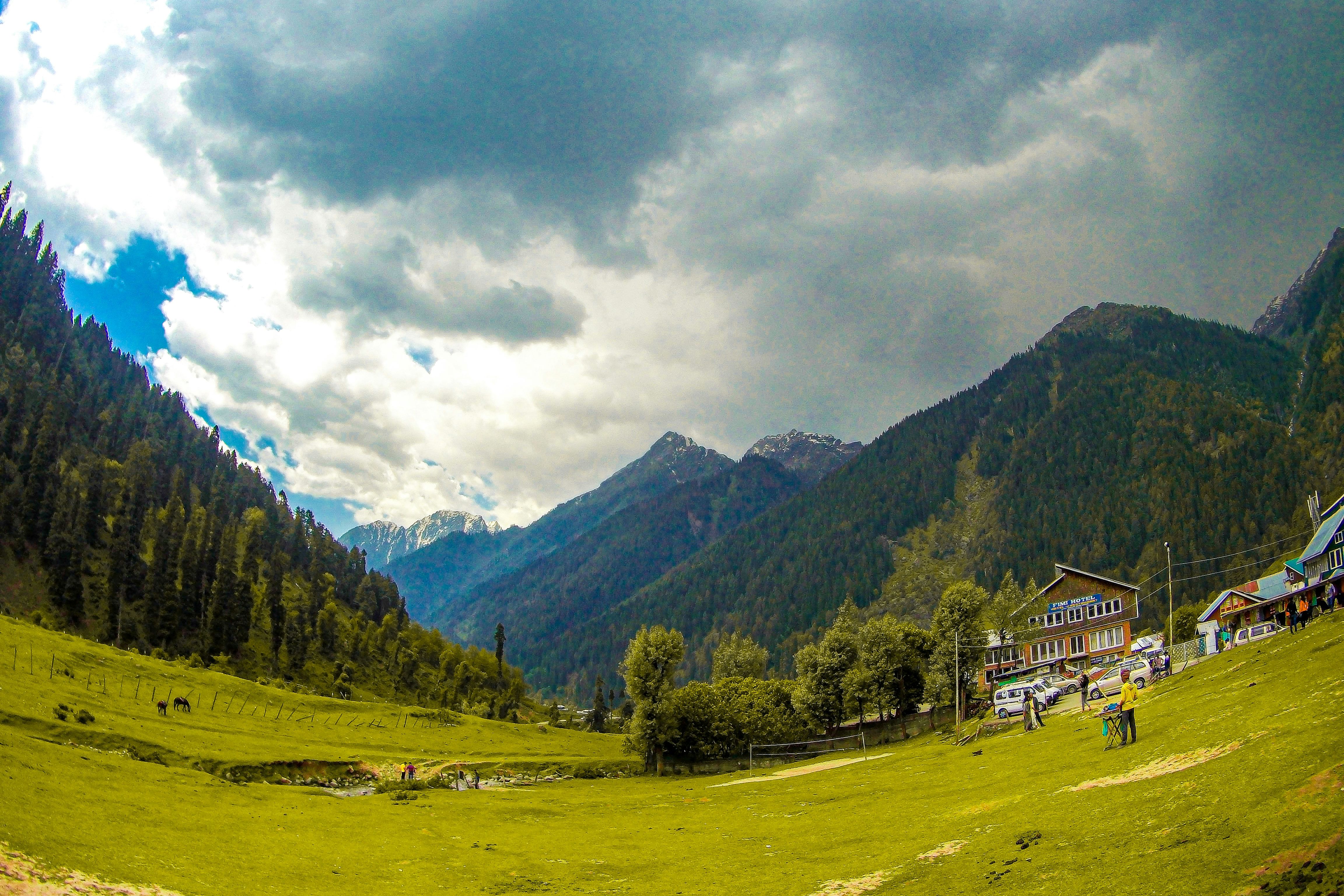 a lush green field in the aru valley with a house in the background