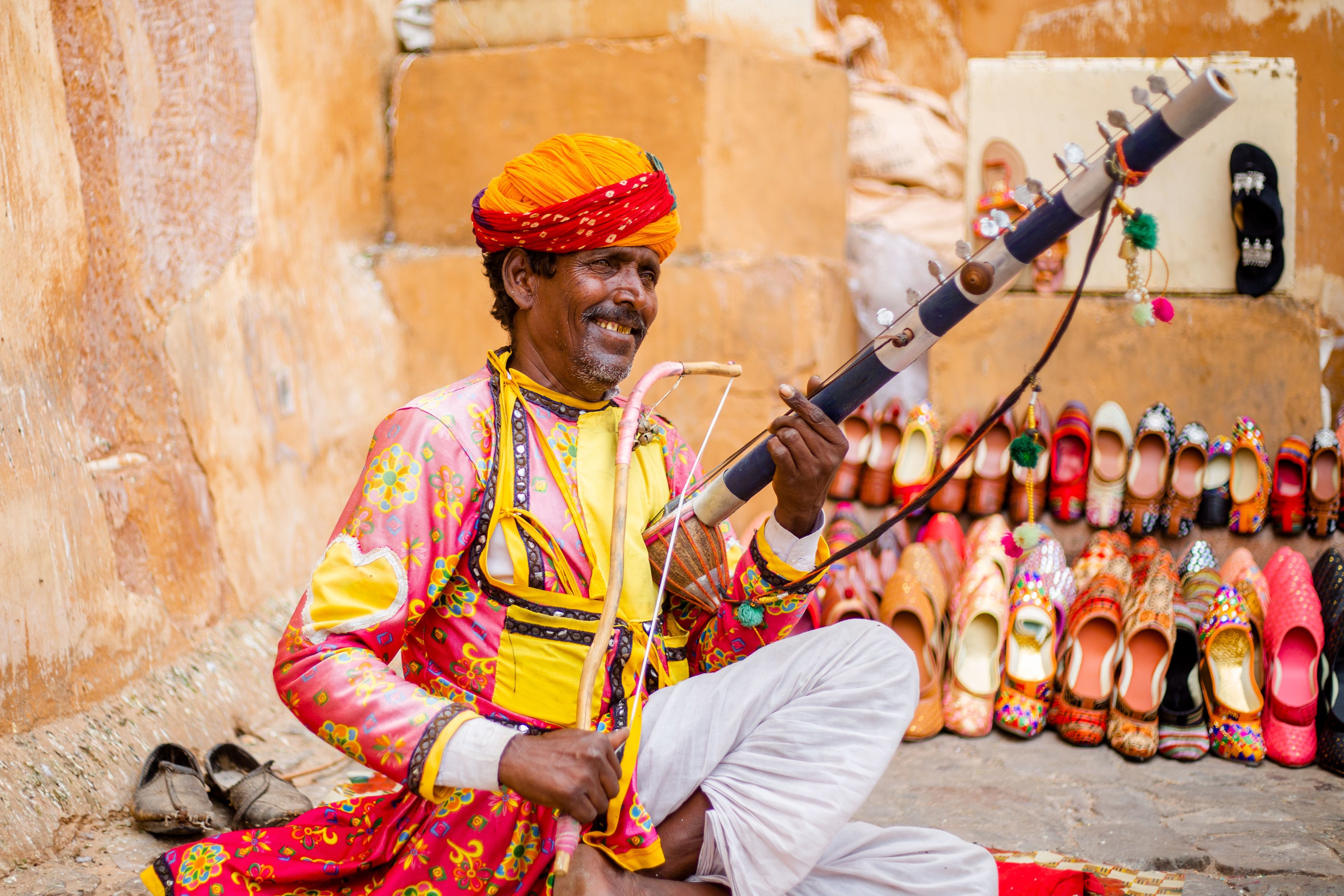 a man in traditional rajasthani clothing playing a musical instrument