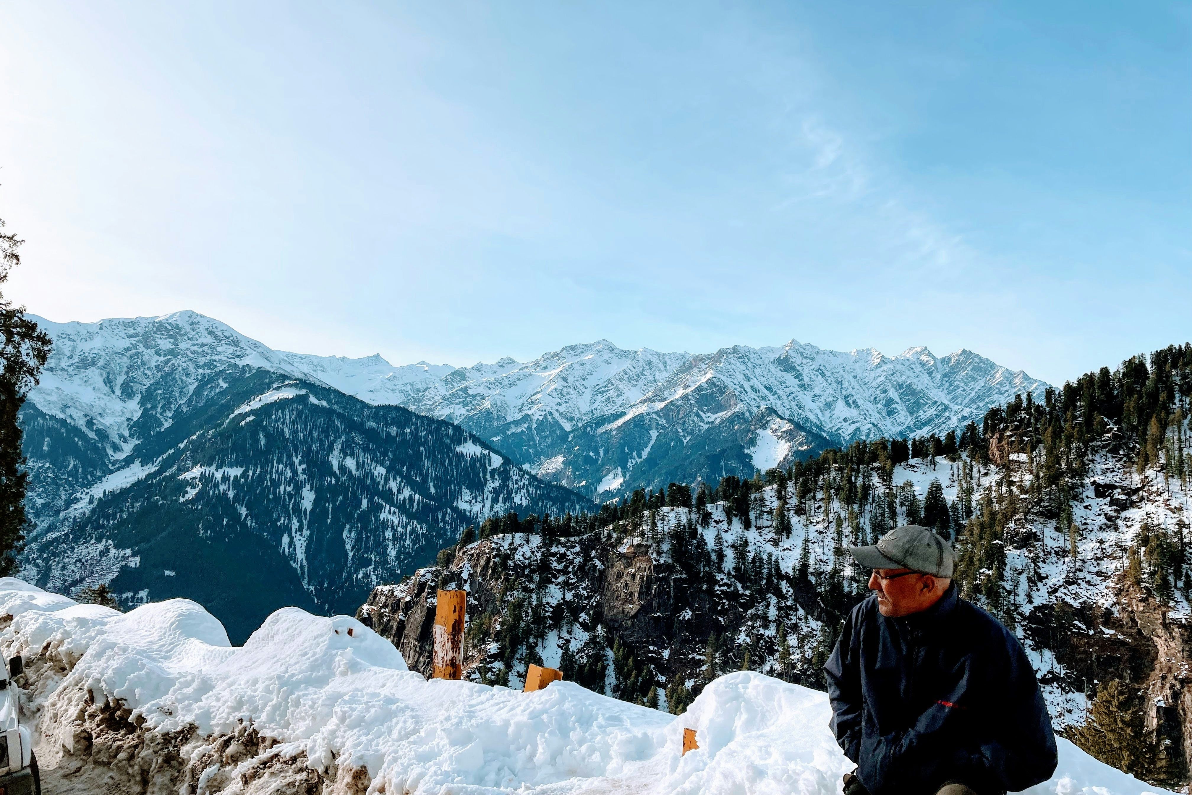 a man sitting on top of a snow covered mountain near hampta pass