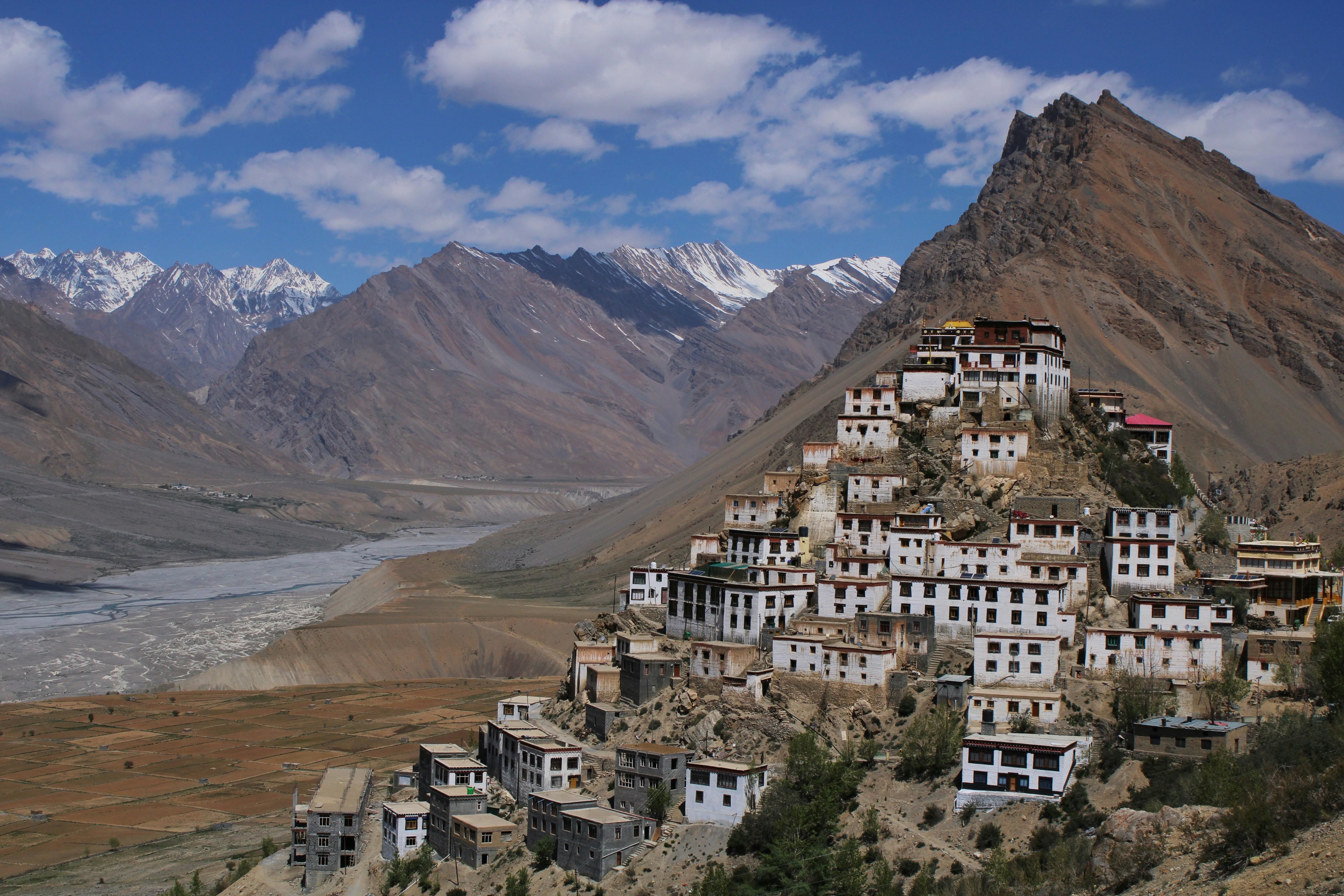 a monastery on a hill top in spiti valley surrounded by mountains