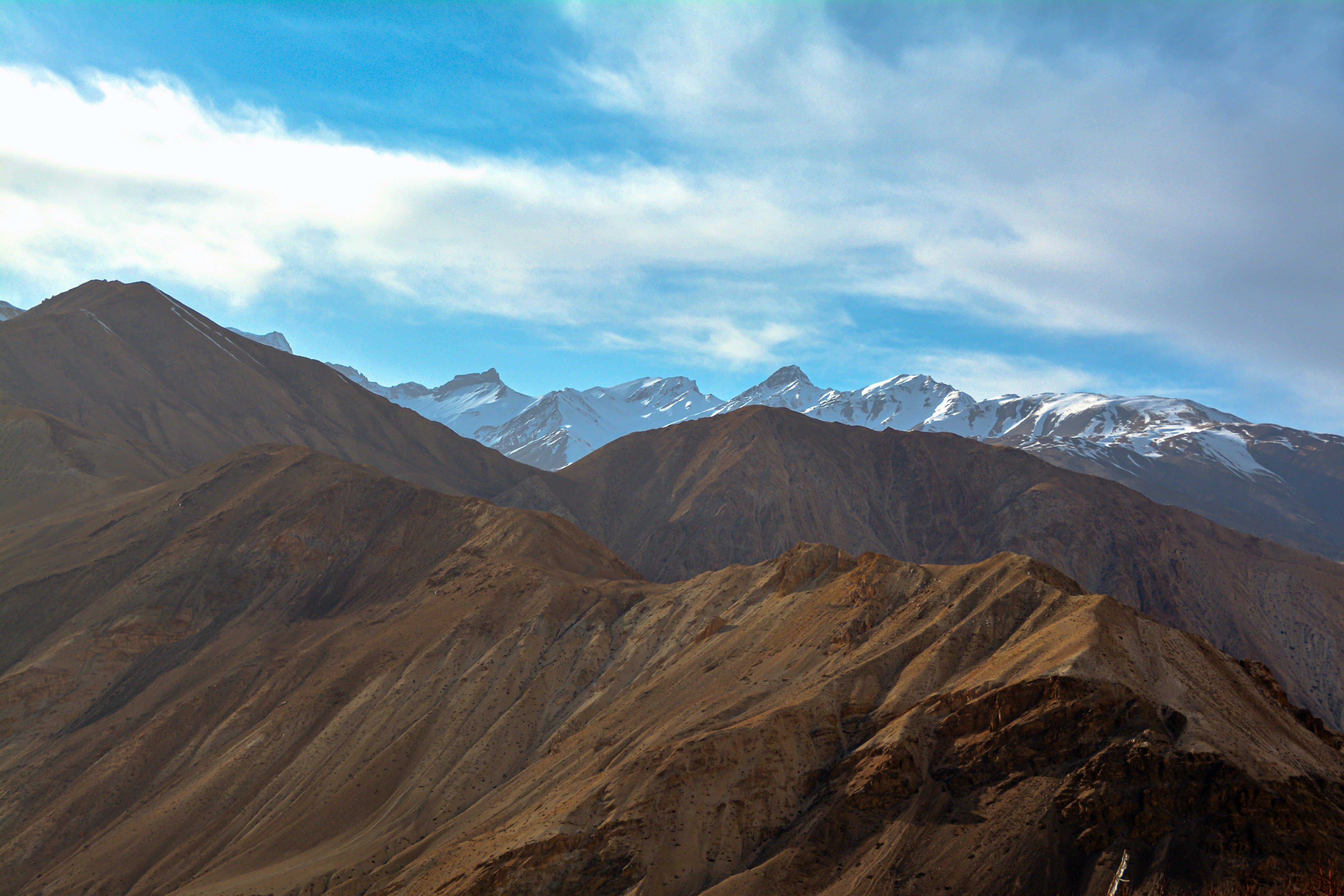 a mountain range with snow capped mountains in the background near nako village in himachal pradesh