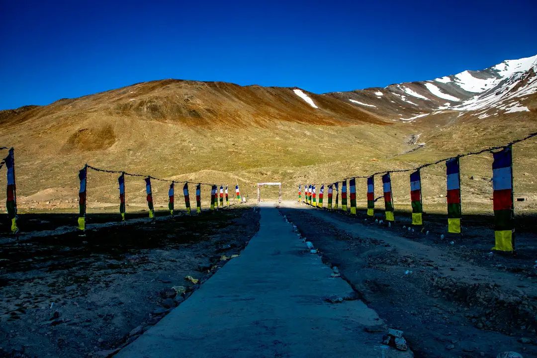 a narrow road near kunzum pass with brown mountains in the backdrop