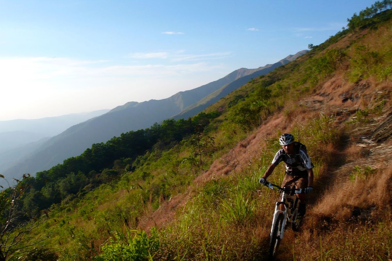a person riding a mountain bike with mountain ranges in the backdrop