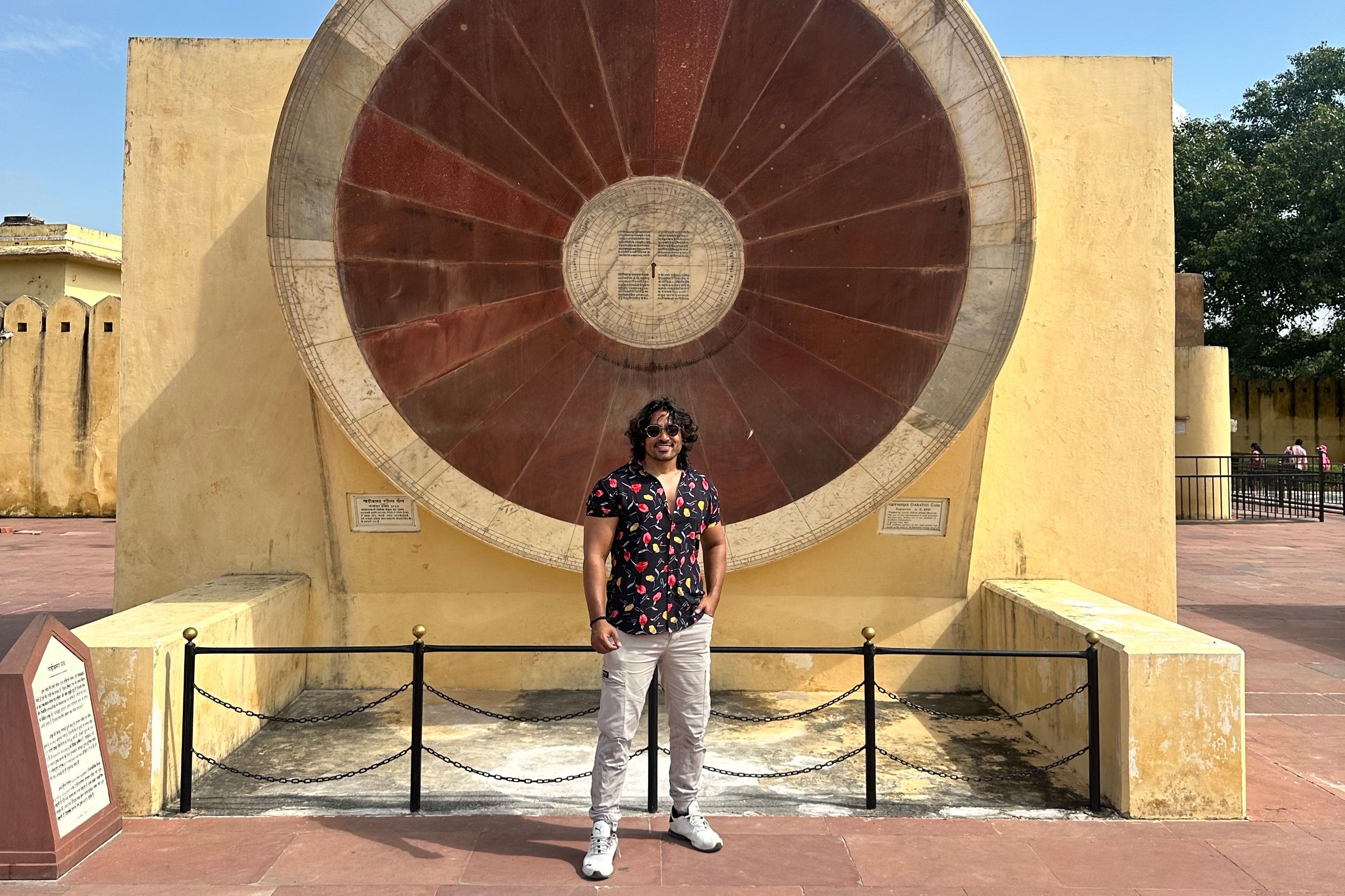 a person standing in front of a large wheel at jantar mantar at jaipur