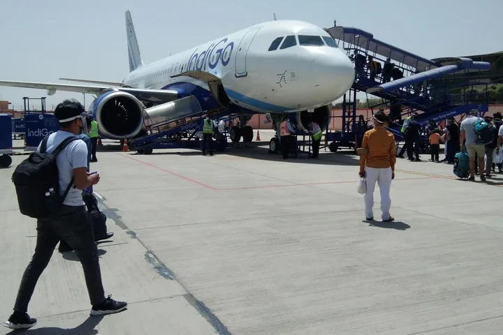 a person standing in front of an aeroplane at jodhpur airport during daytime
