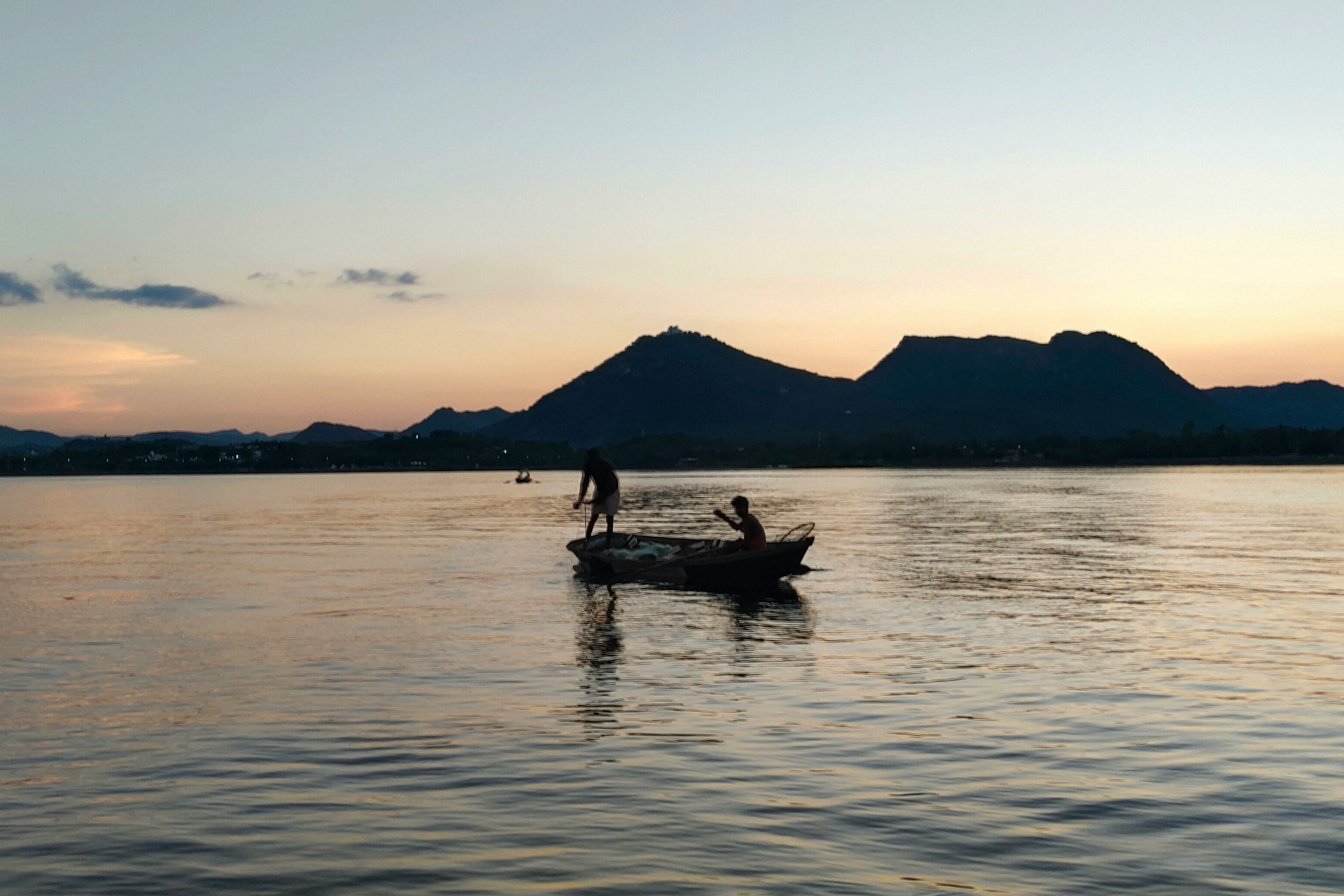 a person standing on a small boat in the fateh sagar lake in udaipur
