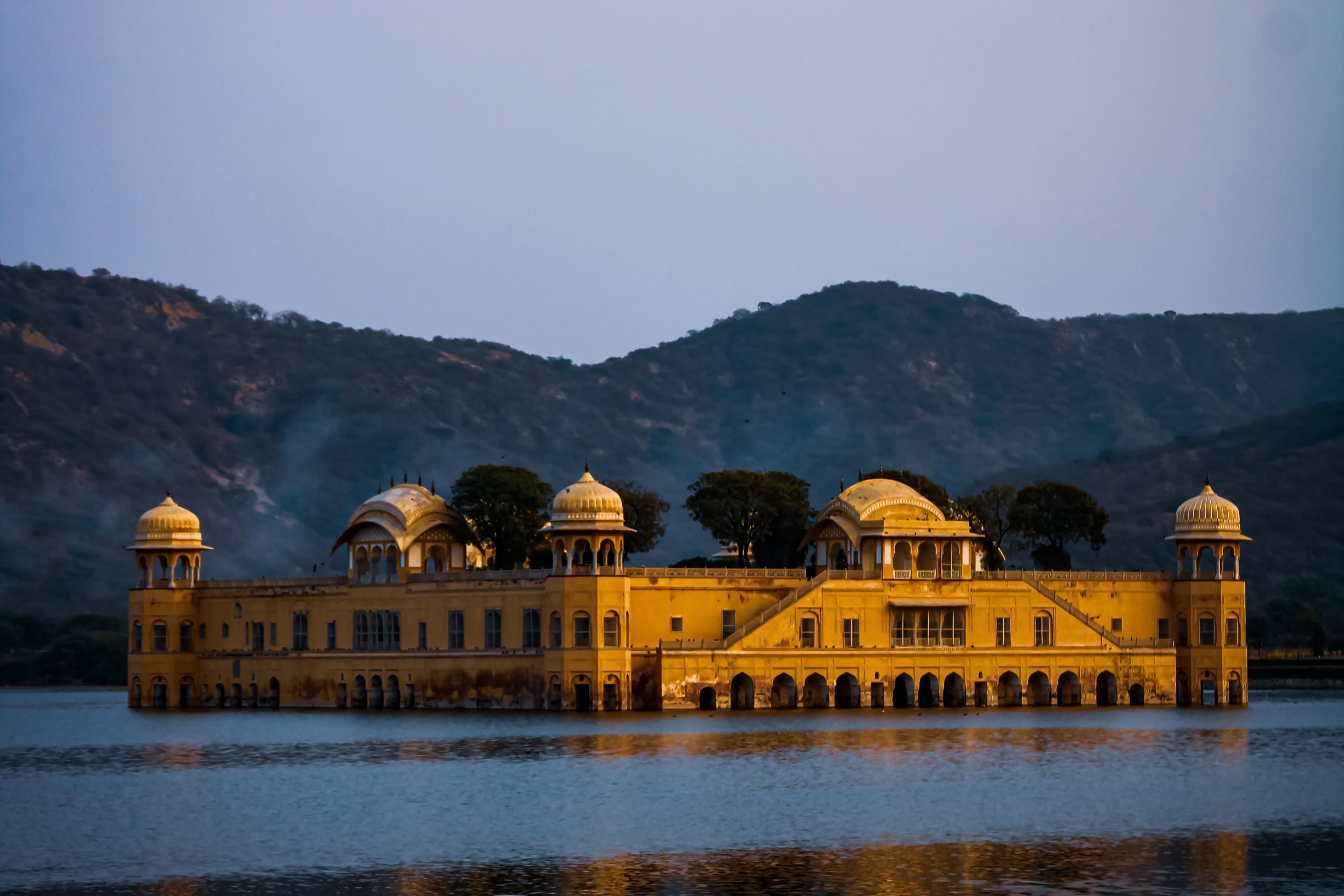 a picturesqe view of the jal mahal reflecting in the man sagar lake in jaipur during daytime