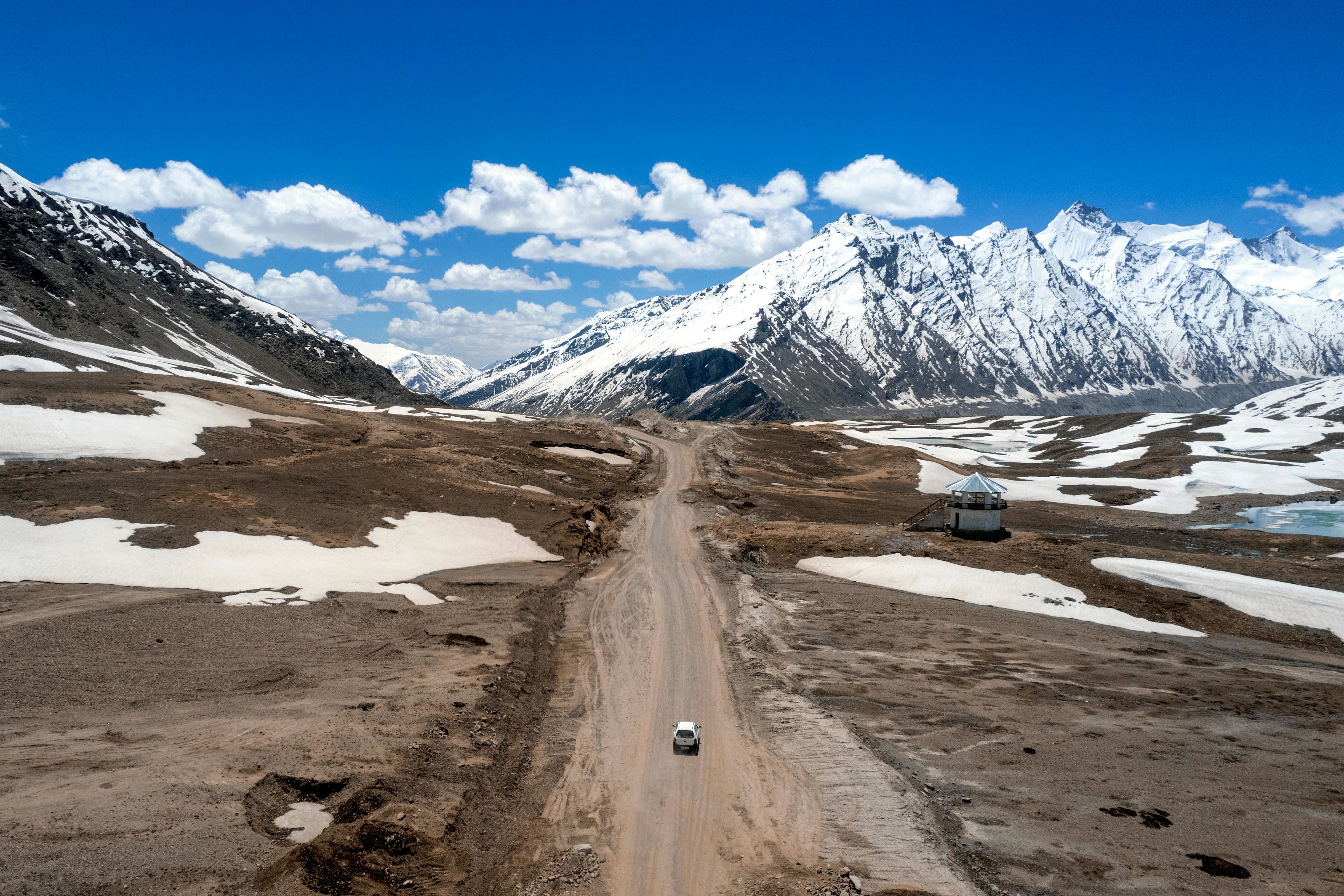 a road from manali to baralacha la pass in the middle of a snowy mountain range