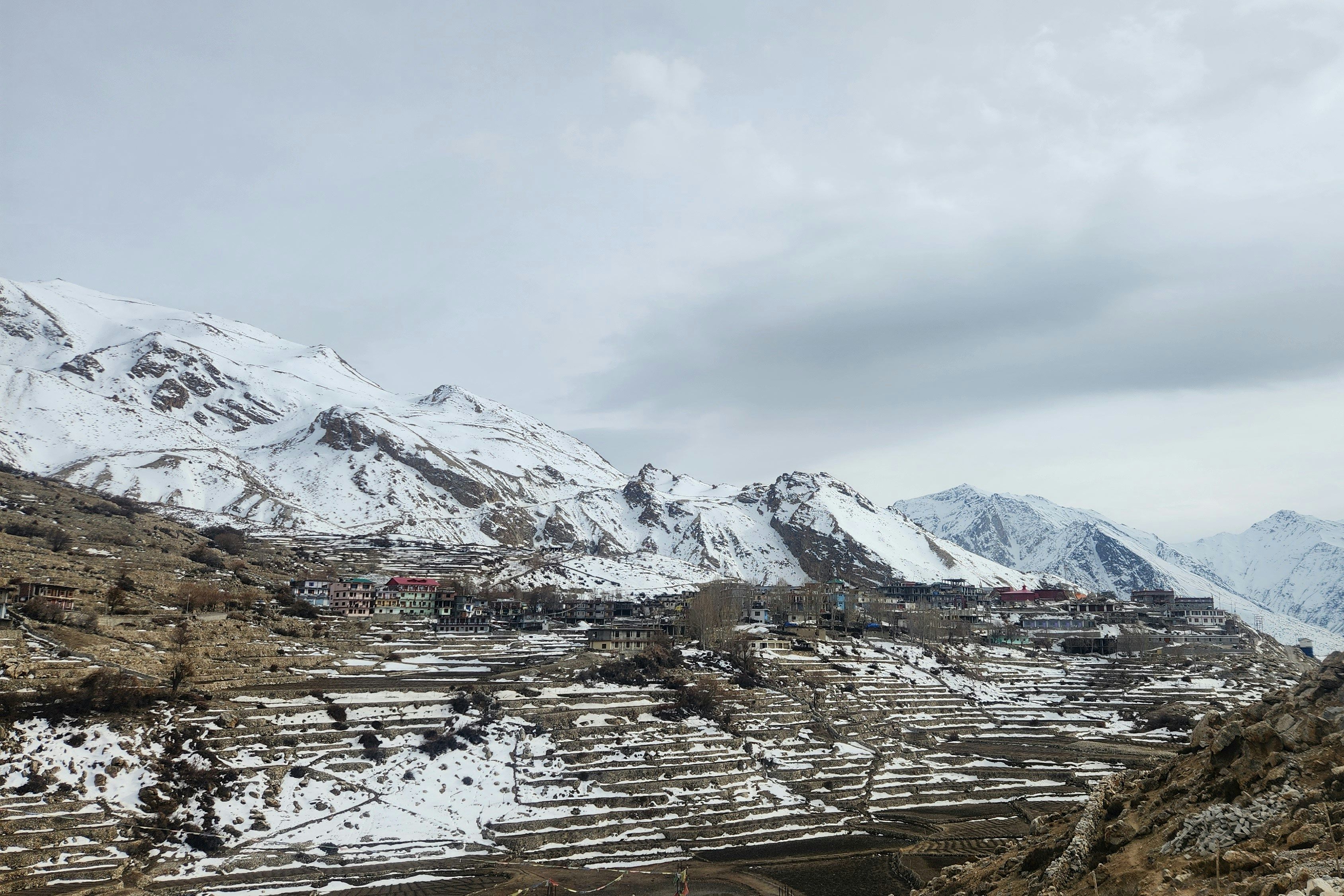 snow covered mountain range with nako village in the foreground
