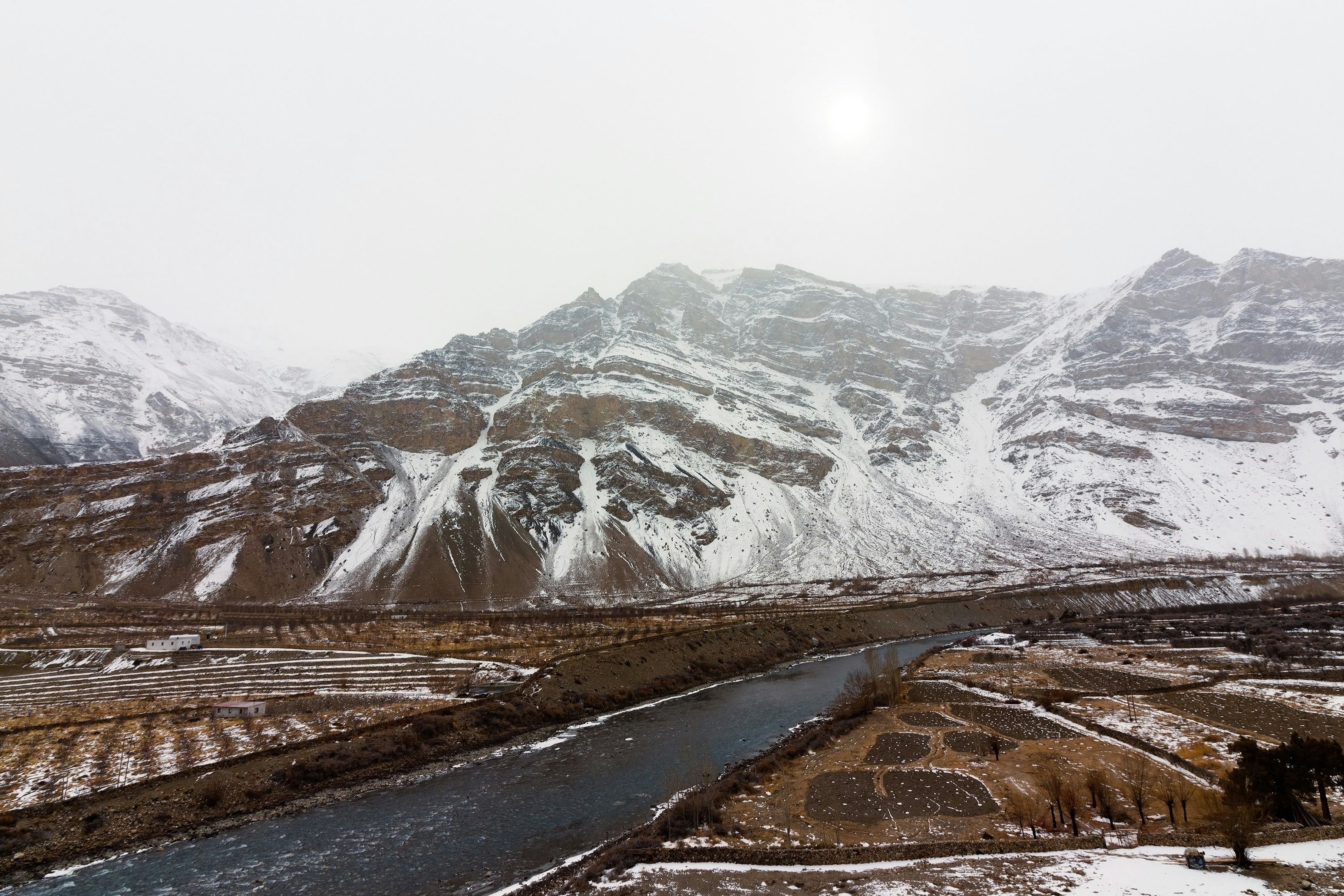 a snow covered mountain range with spiti river running through it near tabo