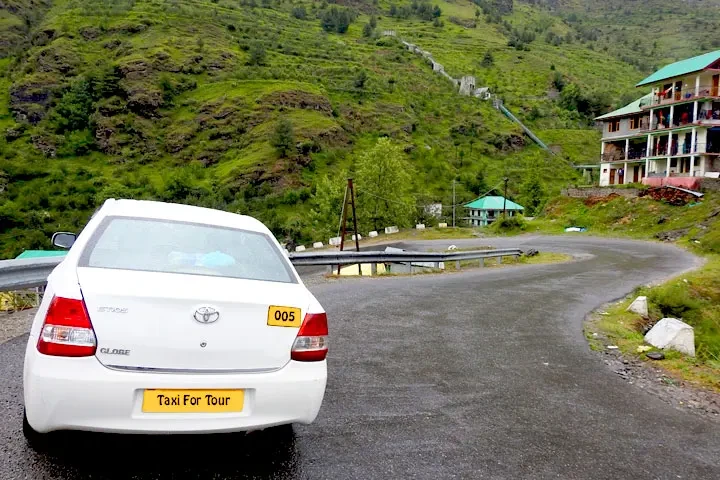 a taxi on a winding road with green mountains in the backdrop