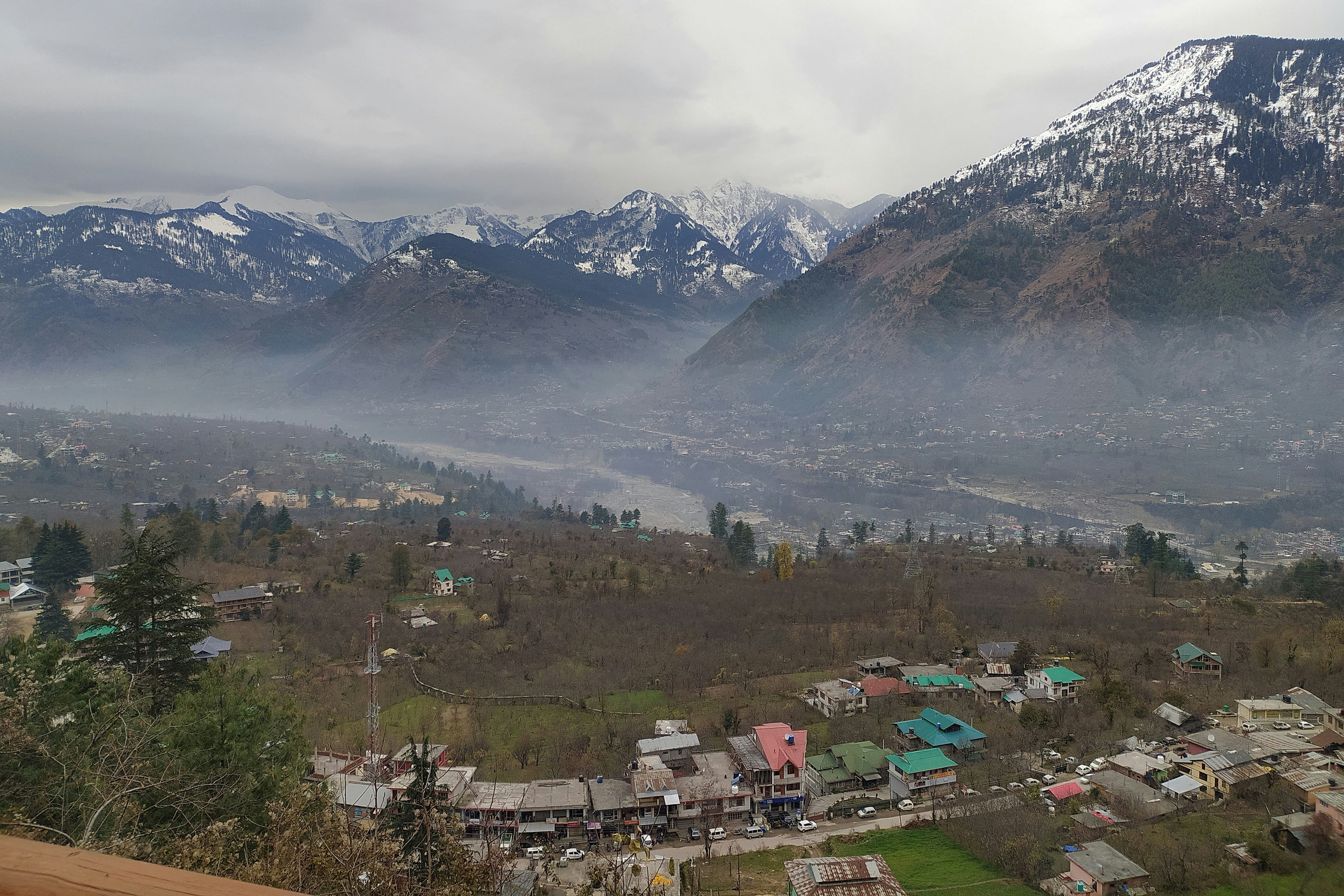 a view of naggar town with mountains in the background