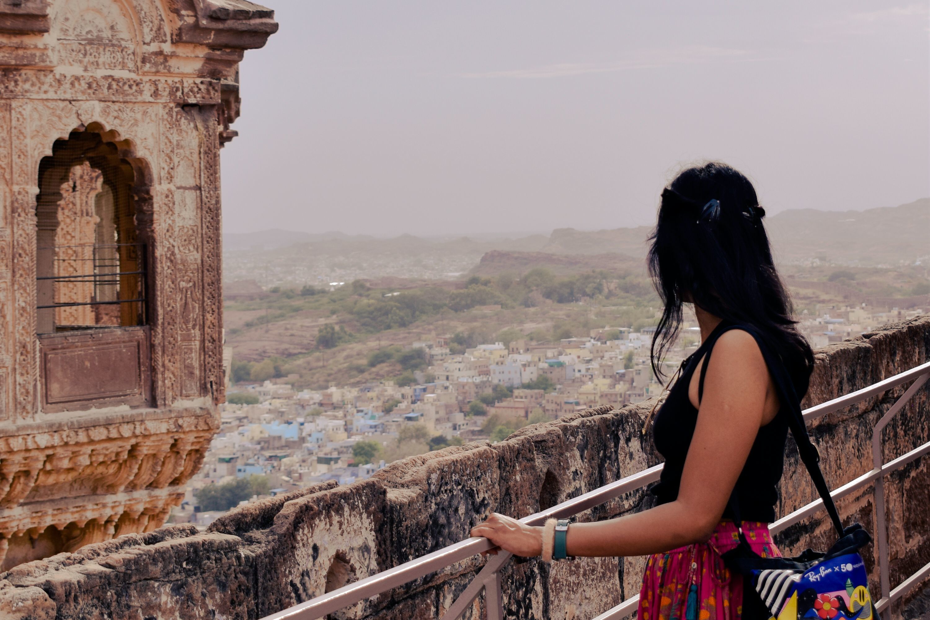 a woman looking out over a city from mehrangarh fort in jodhpur