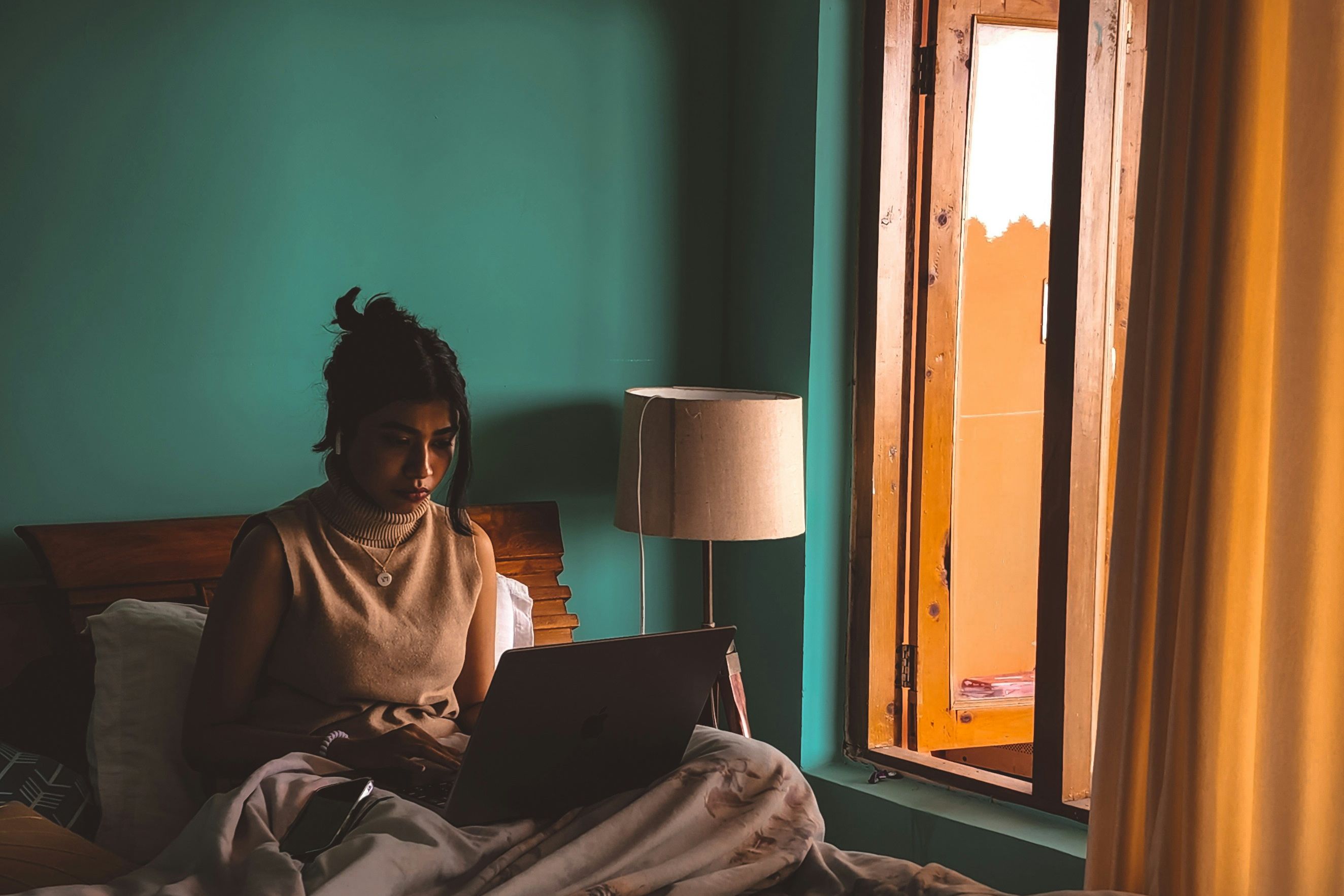 a woman sitting on a bed using a laptop computer