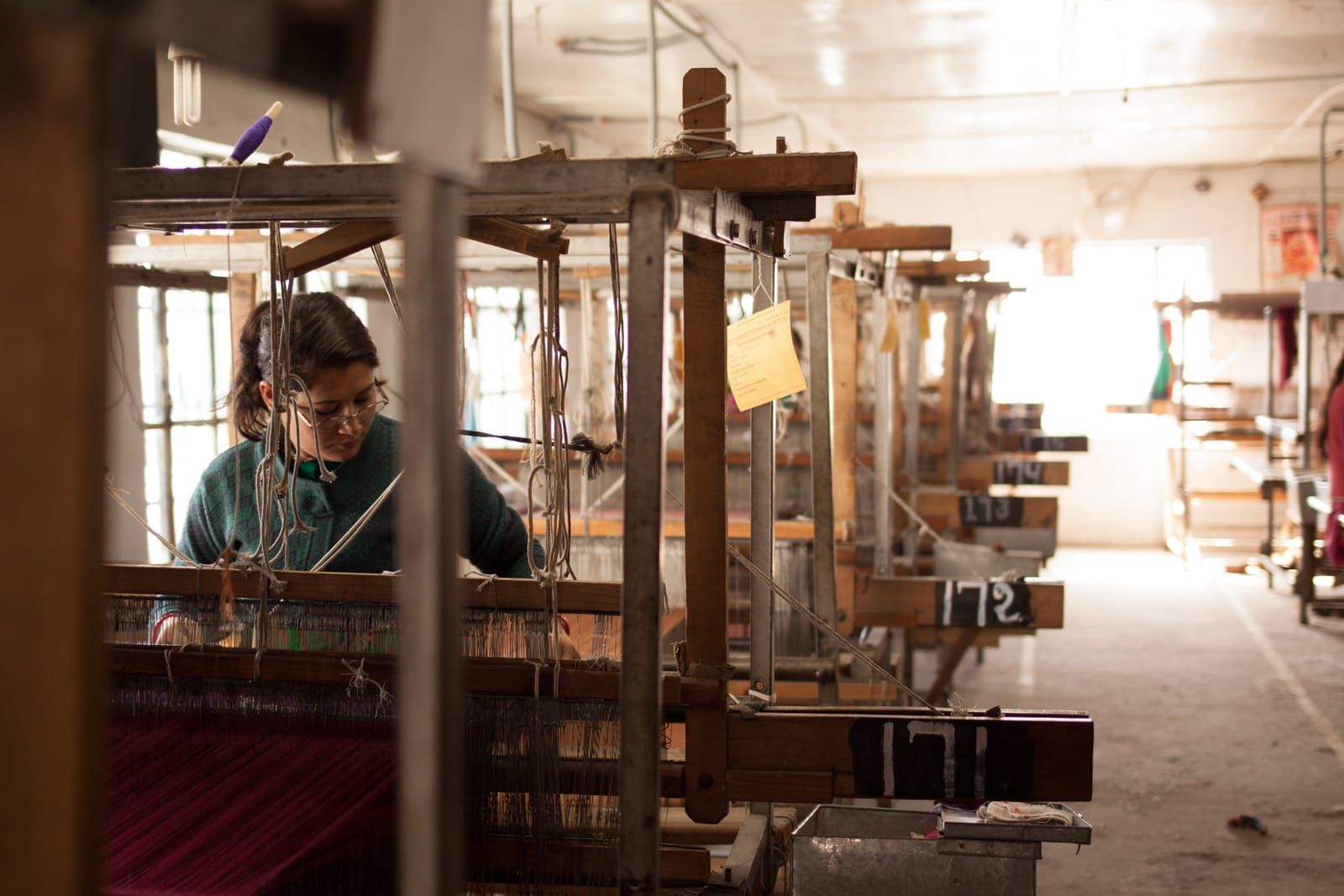 a woman working on a handloom at a shawl factory in kullu