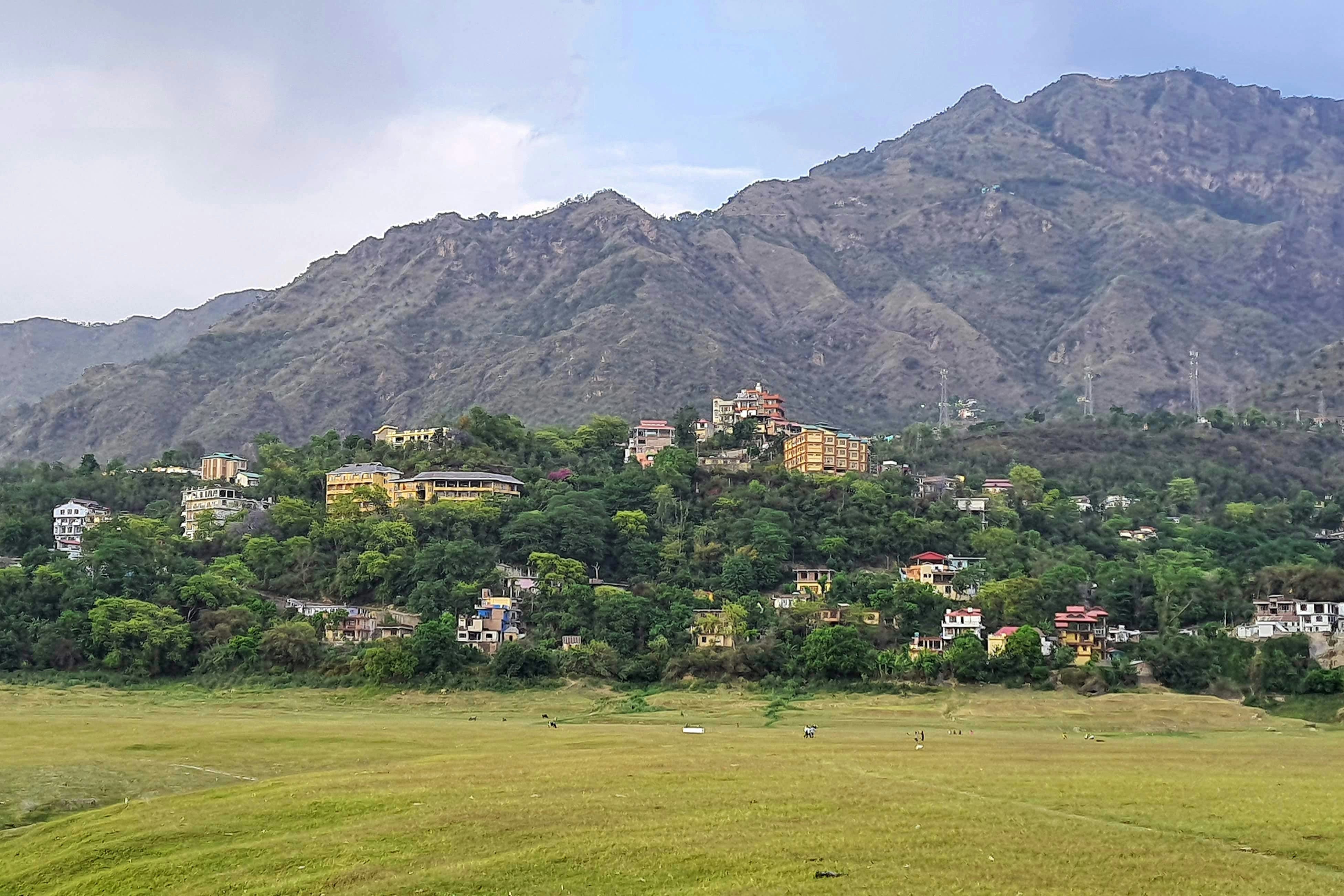 houses on top of a hill with mountains in the background in bilaspur town in himachal pradesh