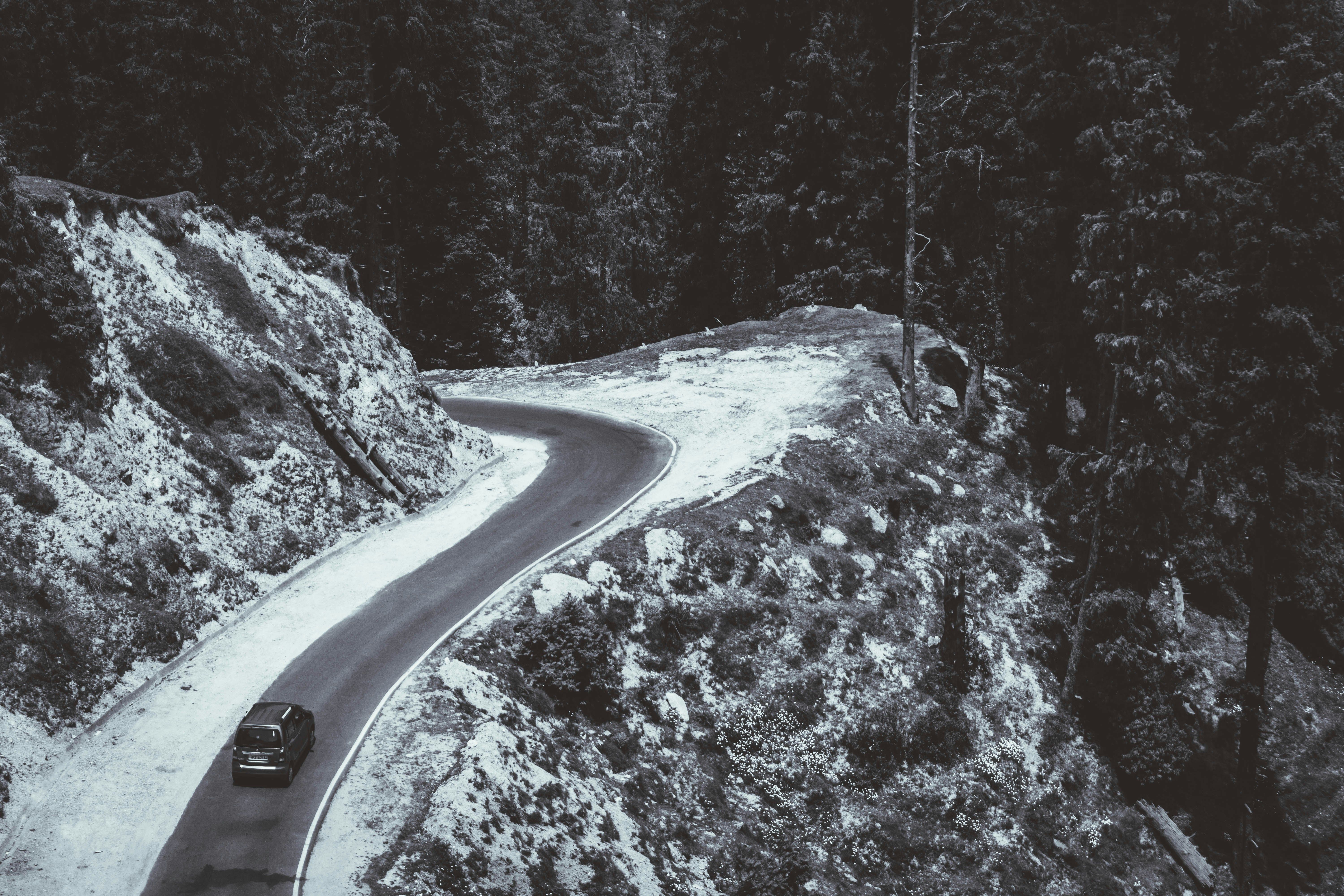a black car on road between snow covered trees during daytime