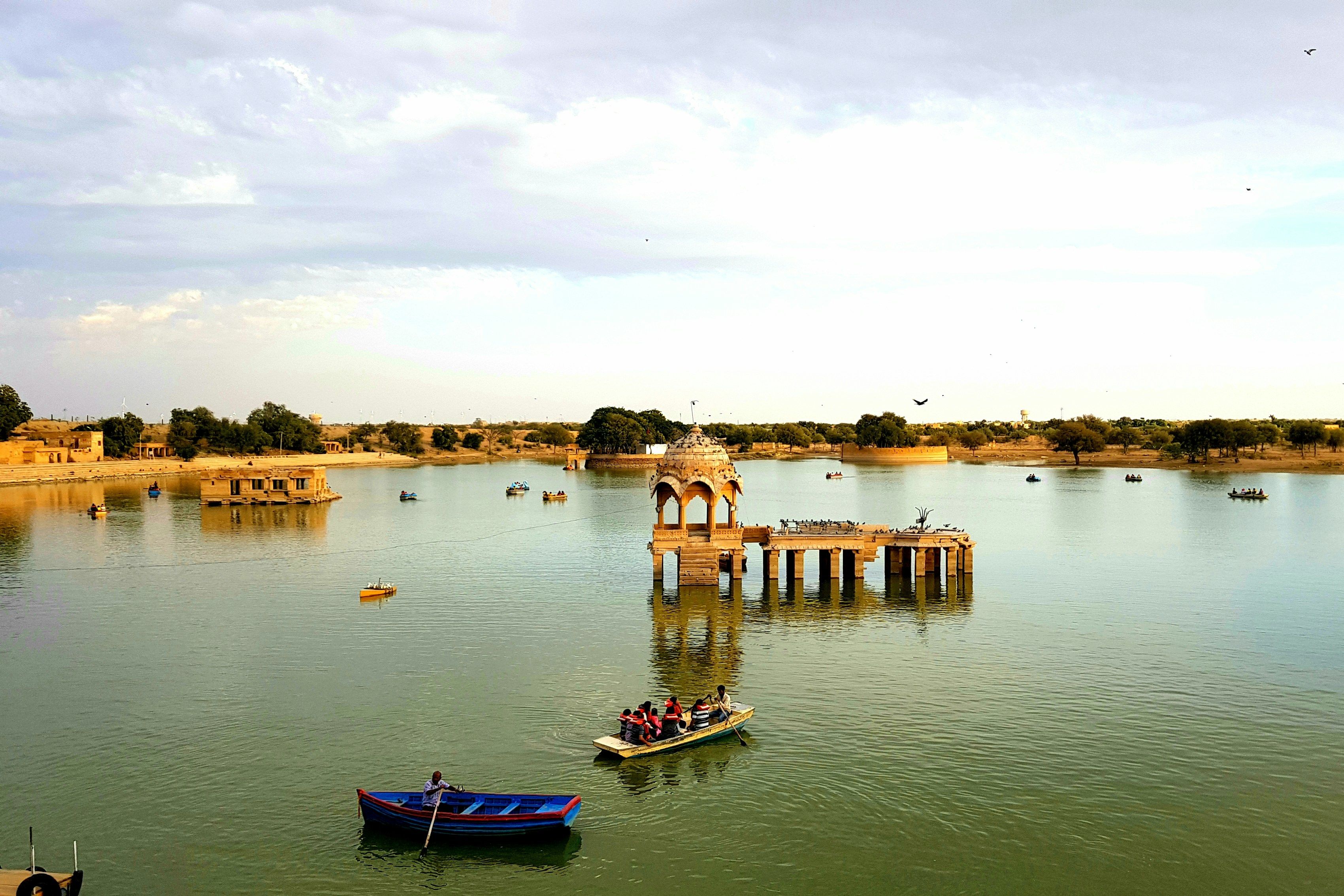 blue and white boat on water near gadisar lake during daytime