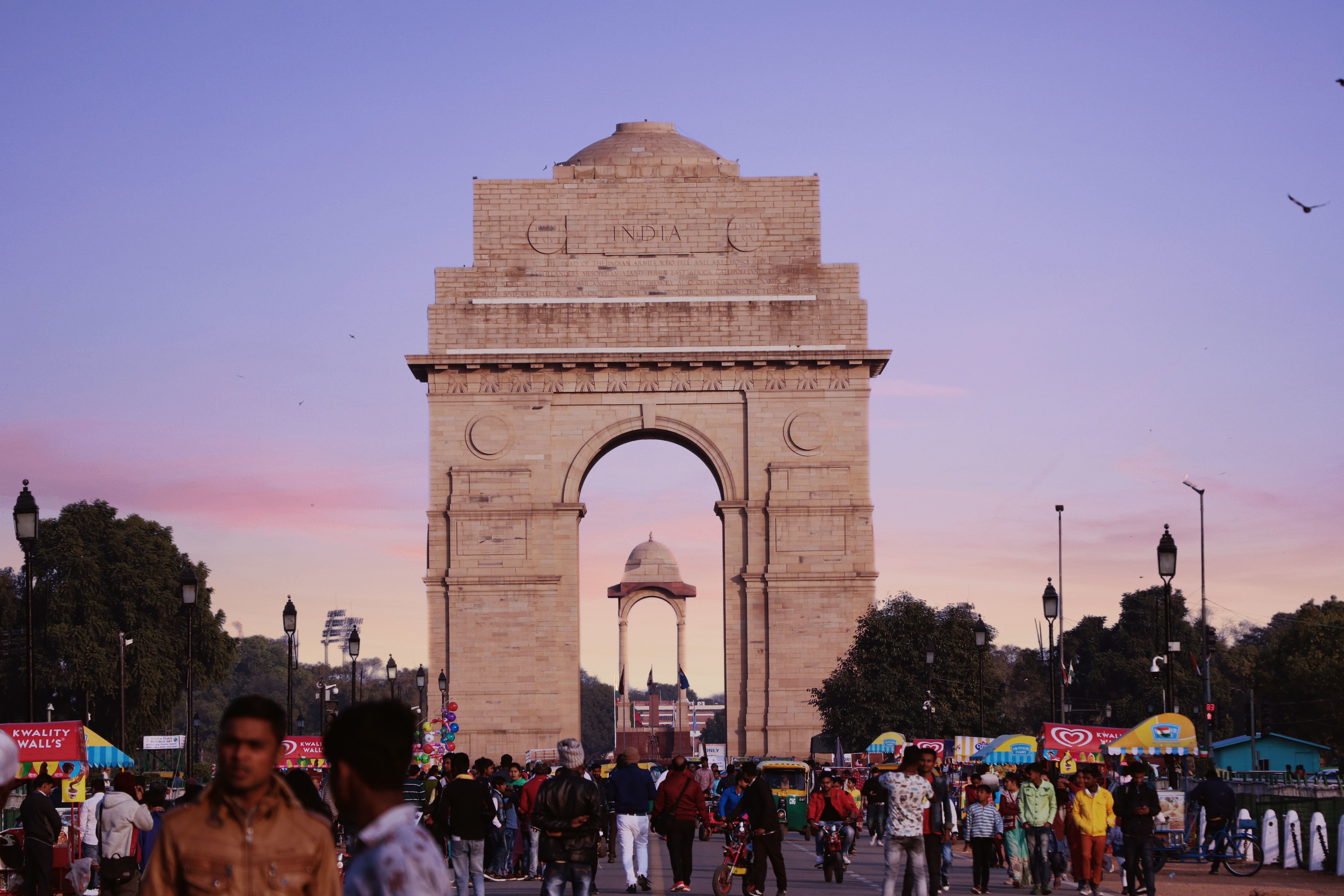 bustling scene at india gate with a vibrant crowd under a colorful sunset sky