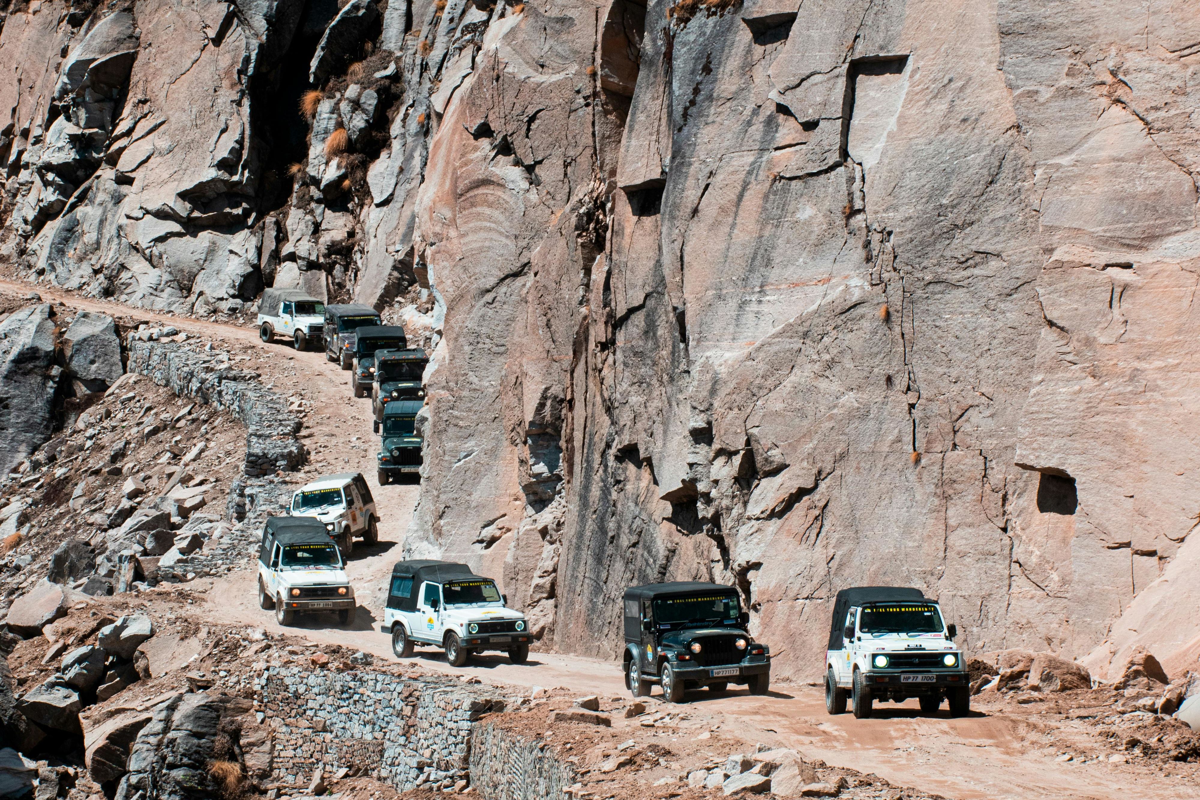 cars on road beside rock formation in spiti valley