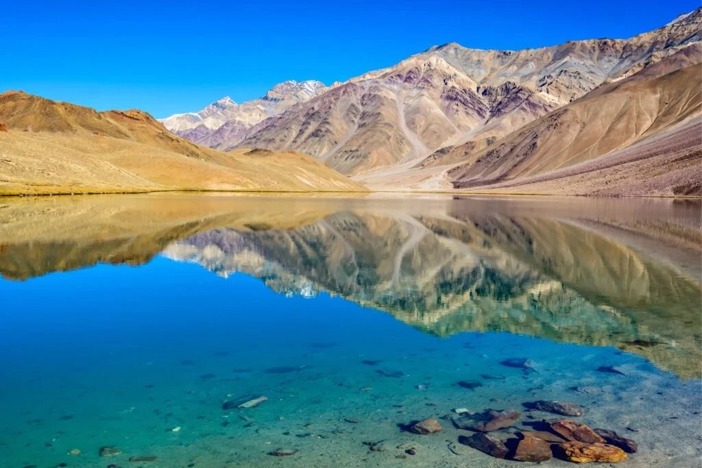chandratal lake in the foreground of mountains in daylight