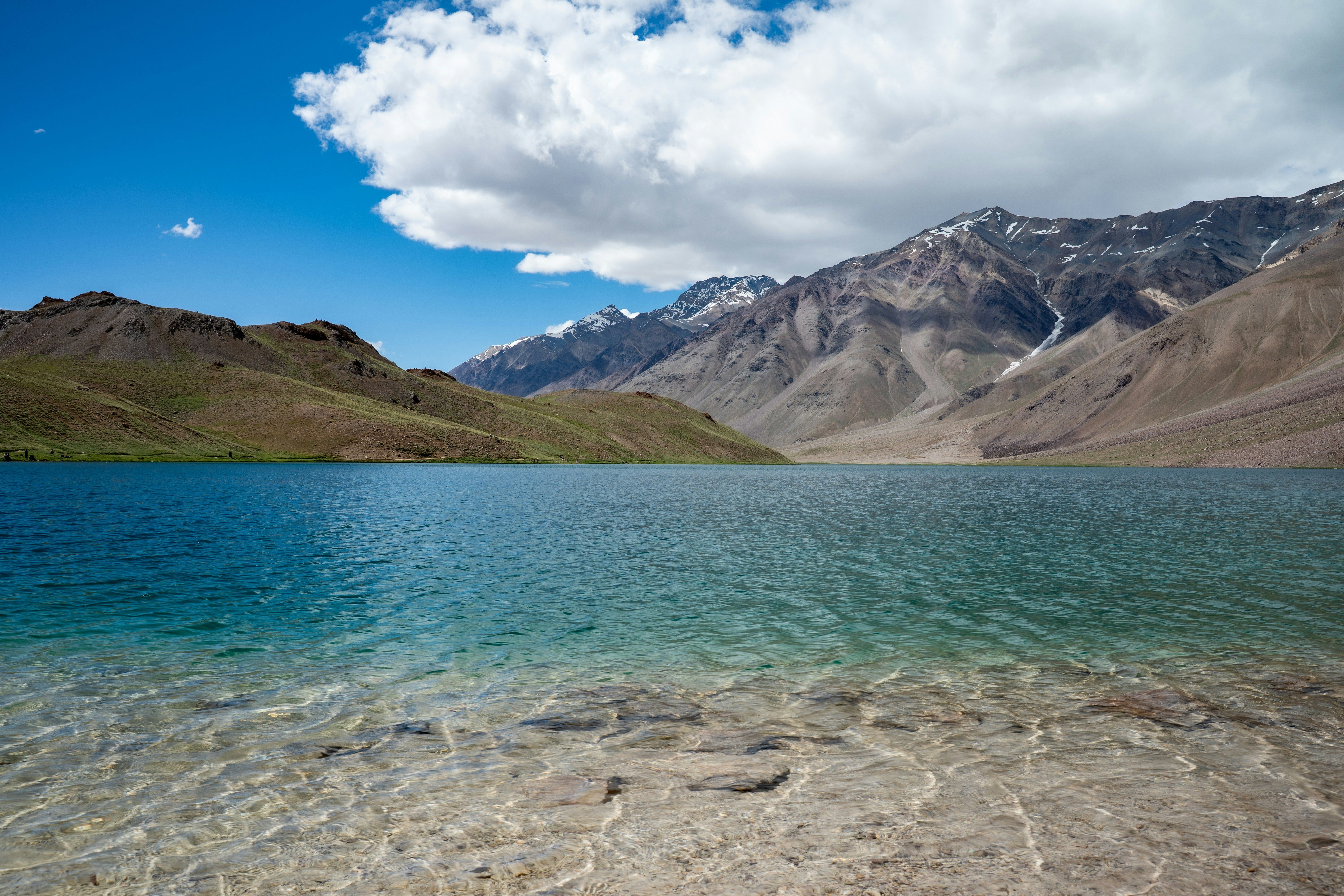clear blue waters of chandratal lake surrounded by mountains under a bright sky