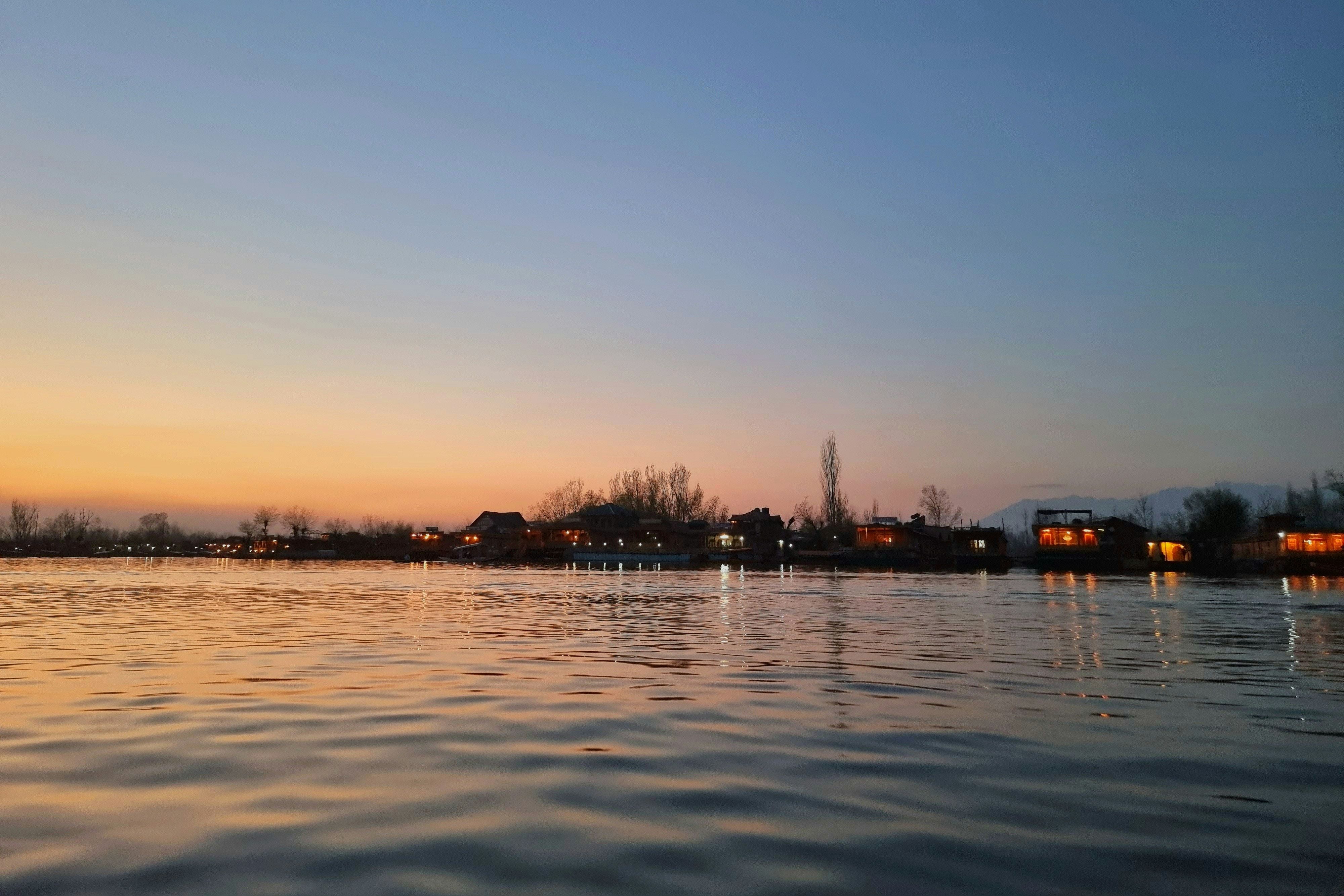 dal lake in srinagar with buildings in the background during evening