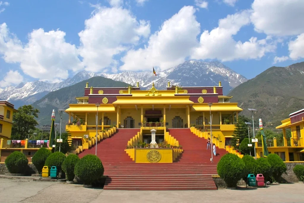 a view of the dalai lama temple in dharamshala with snow capped mountains in the backdrop