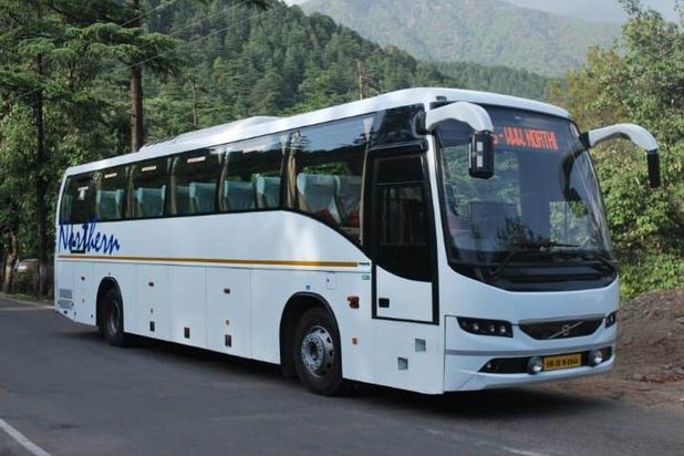 a white volvo bus plying in between delhi and dharamshala