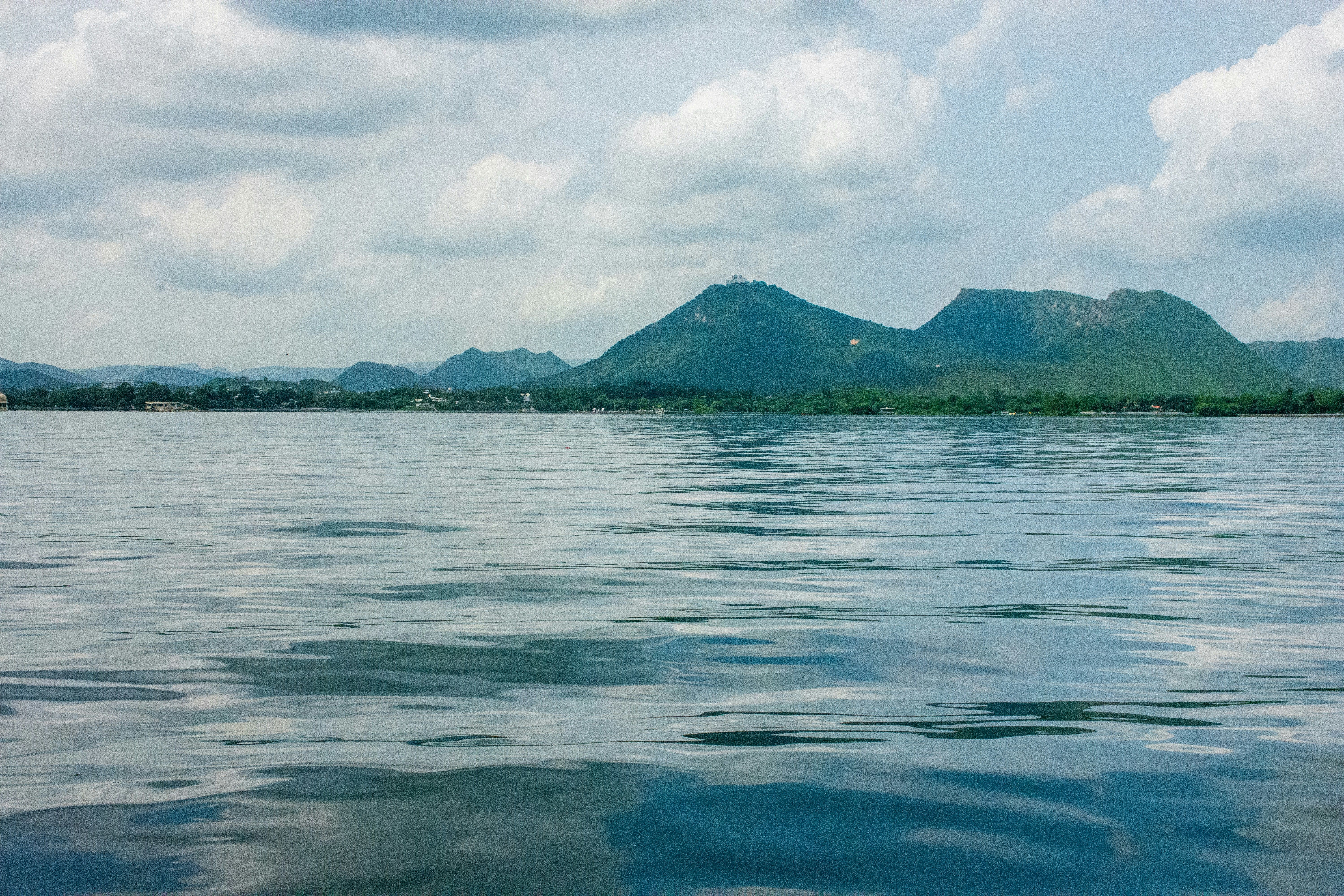 view of fateh sagar lake with green mountains in the background