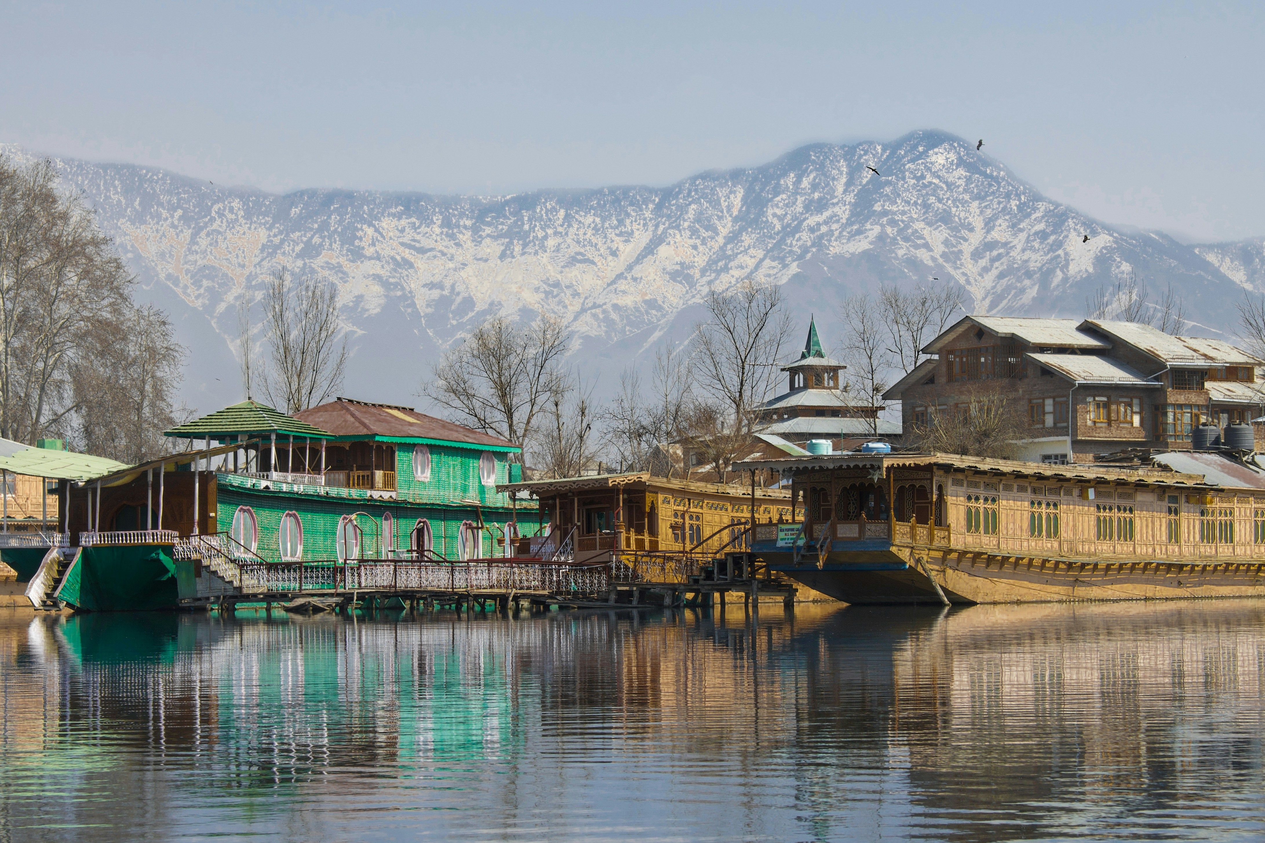 green and brown wooden houseboat near snow covered mountain during daytime