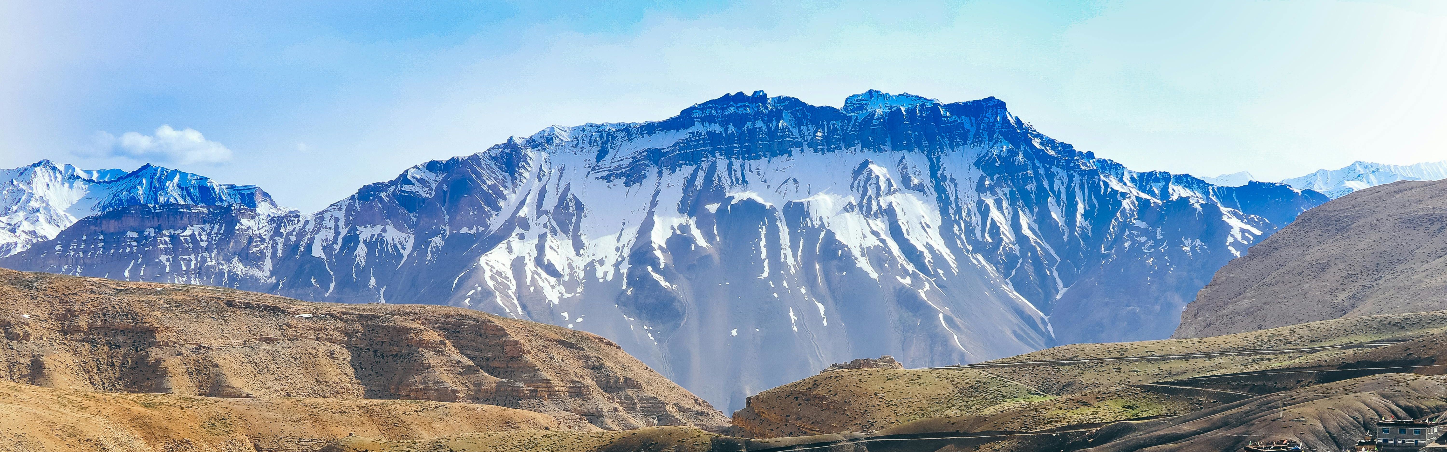 green grass fields near snow covered mountains in spiti valley