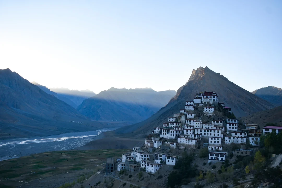a view of key monastery with mountains in the backdrop during evening