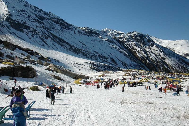 people walking on snow near a snow covered hill top near manali