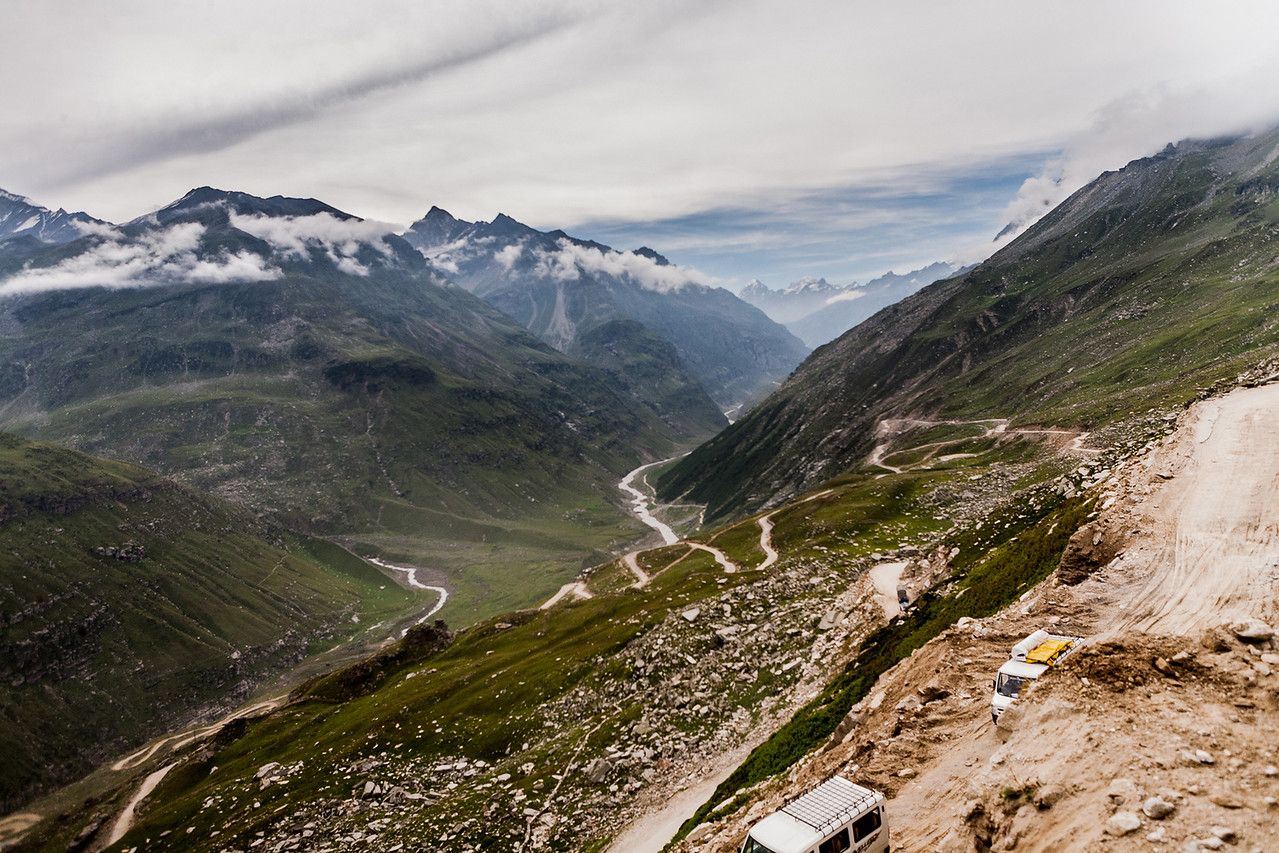 two vehicles passing through narrow winding roads on mountains