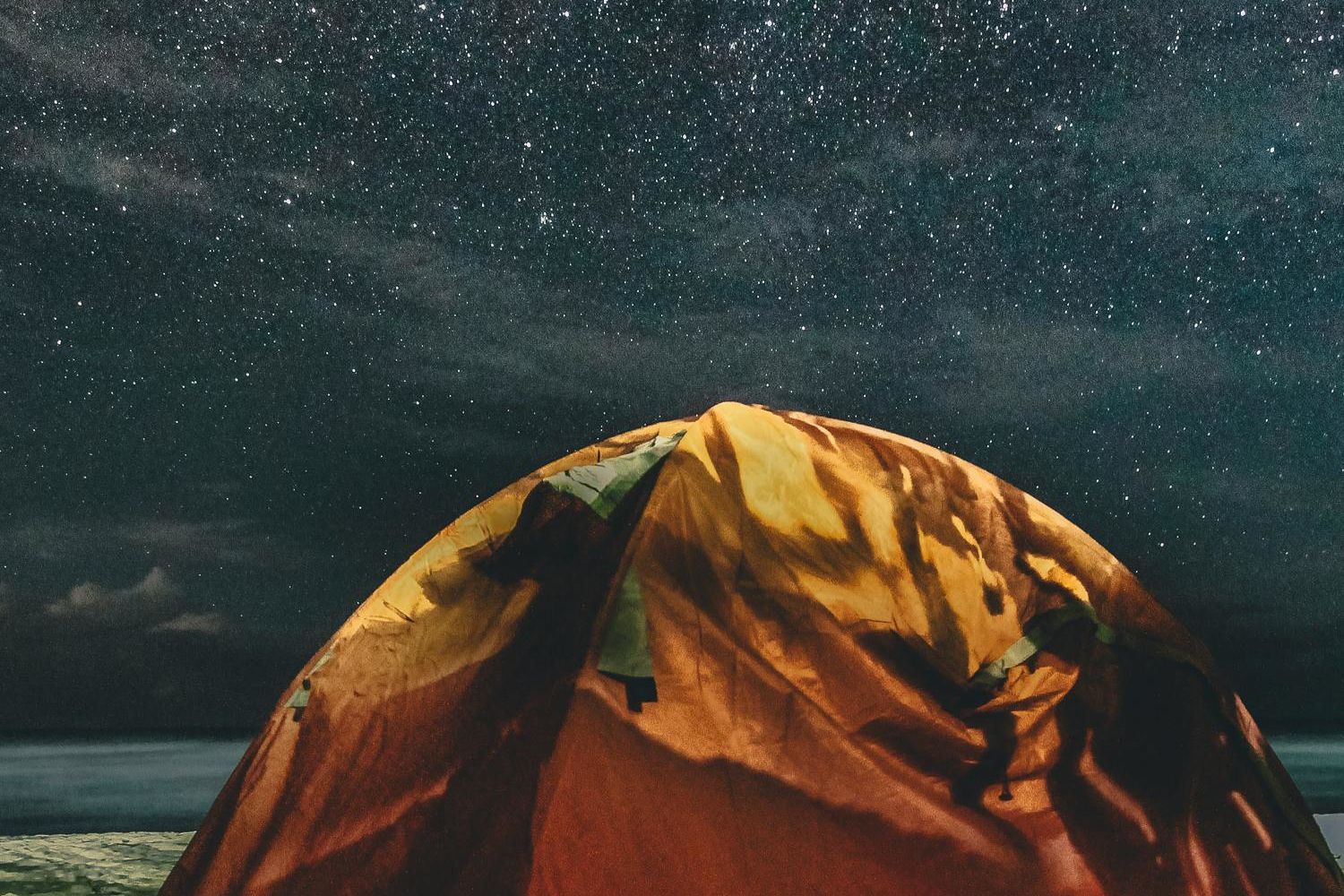 orange and green camping tent under starry night sky