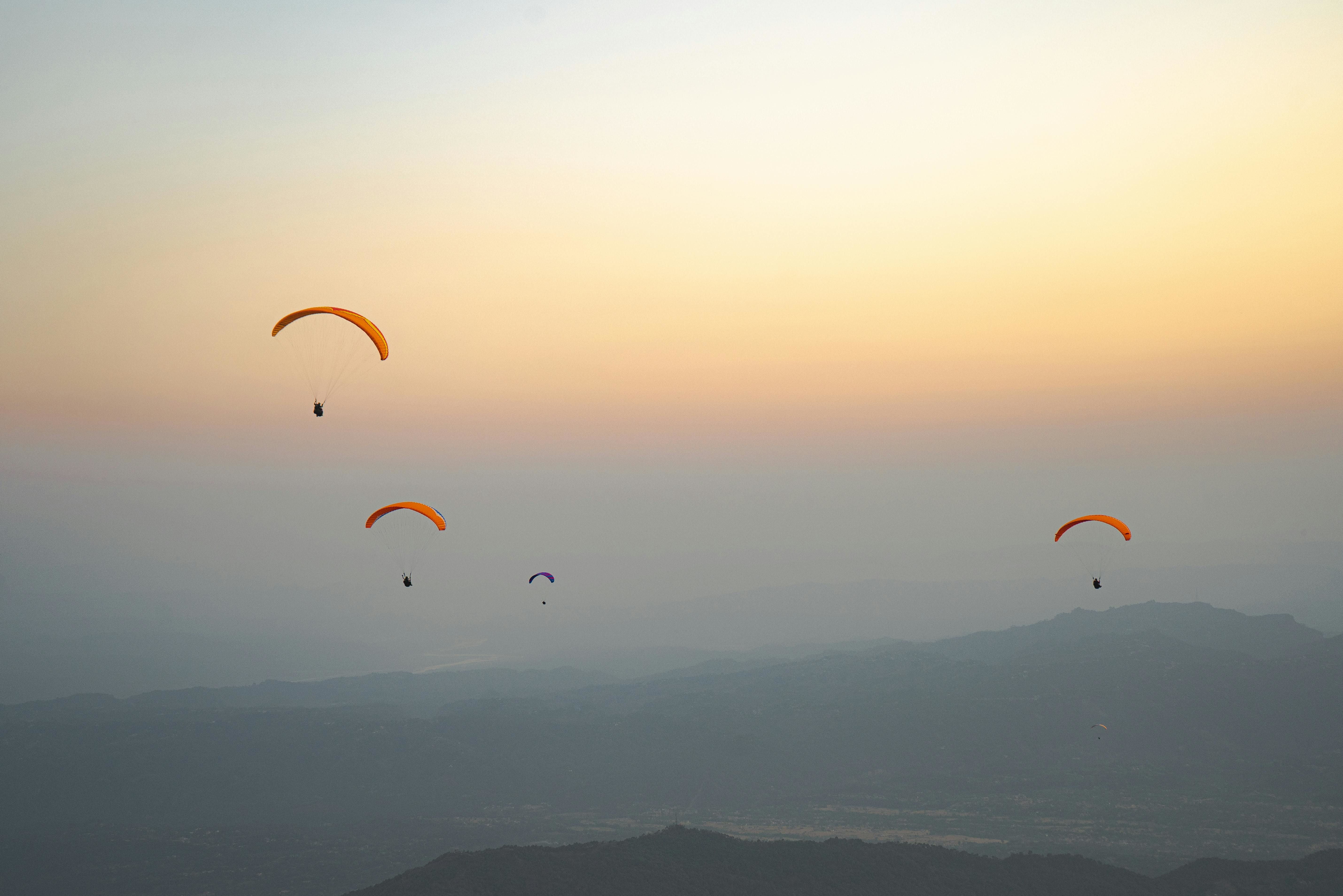 people parachuting over hills at sunset near bir