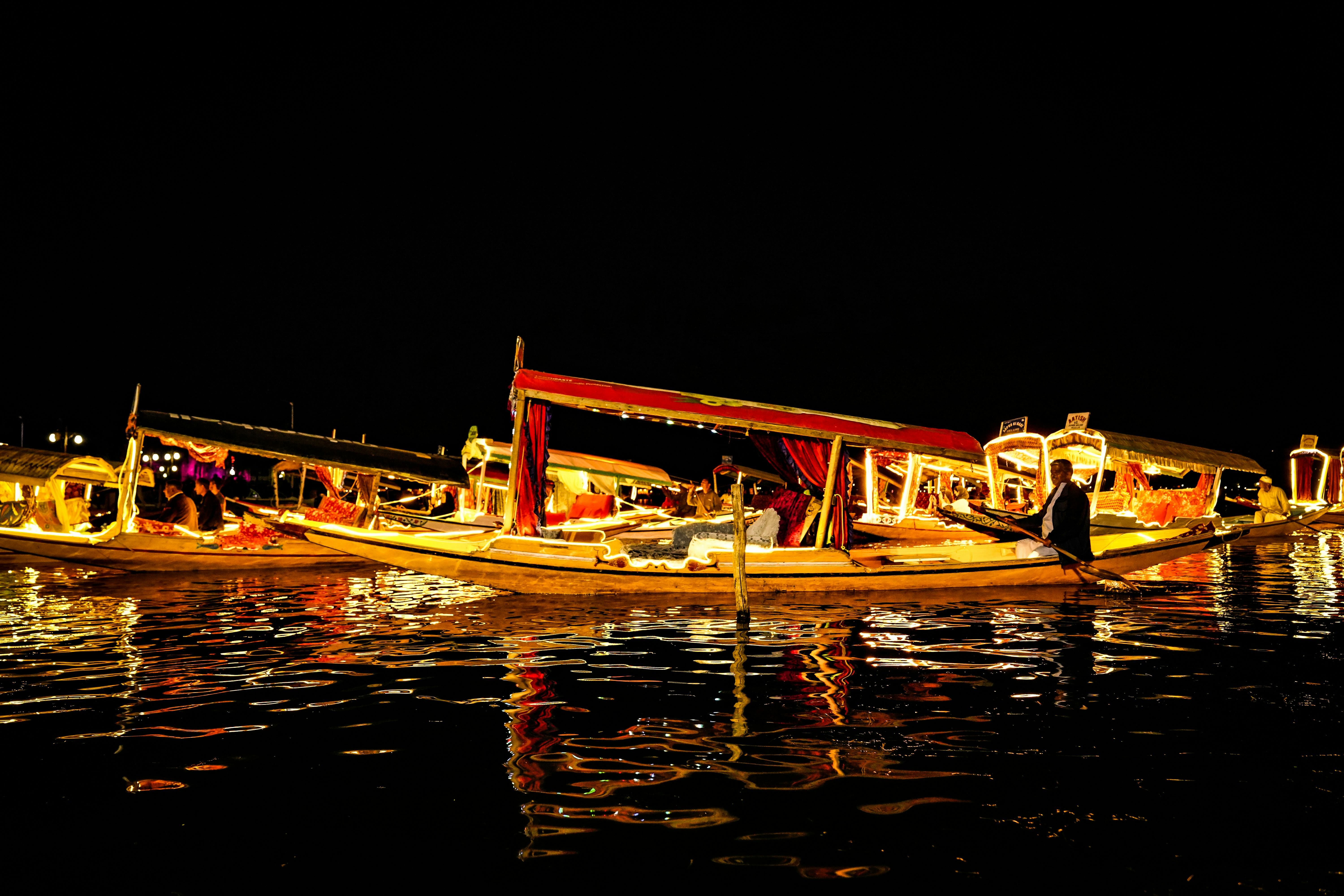 people riding on yellow shikara boats on dal lake during night time in srinagar