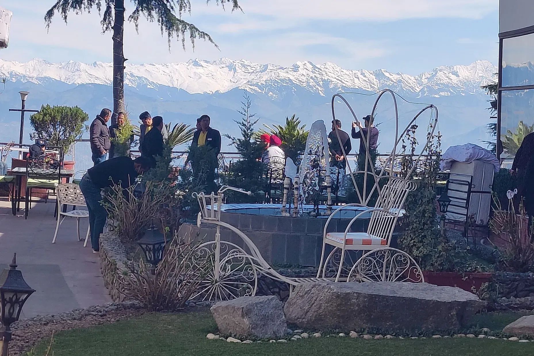 people standing on the terrace of hotel mount view in dalhousie with snow capped mountains in the backdrop