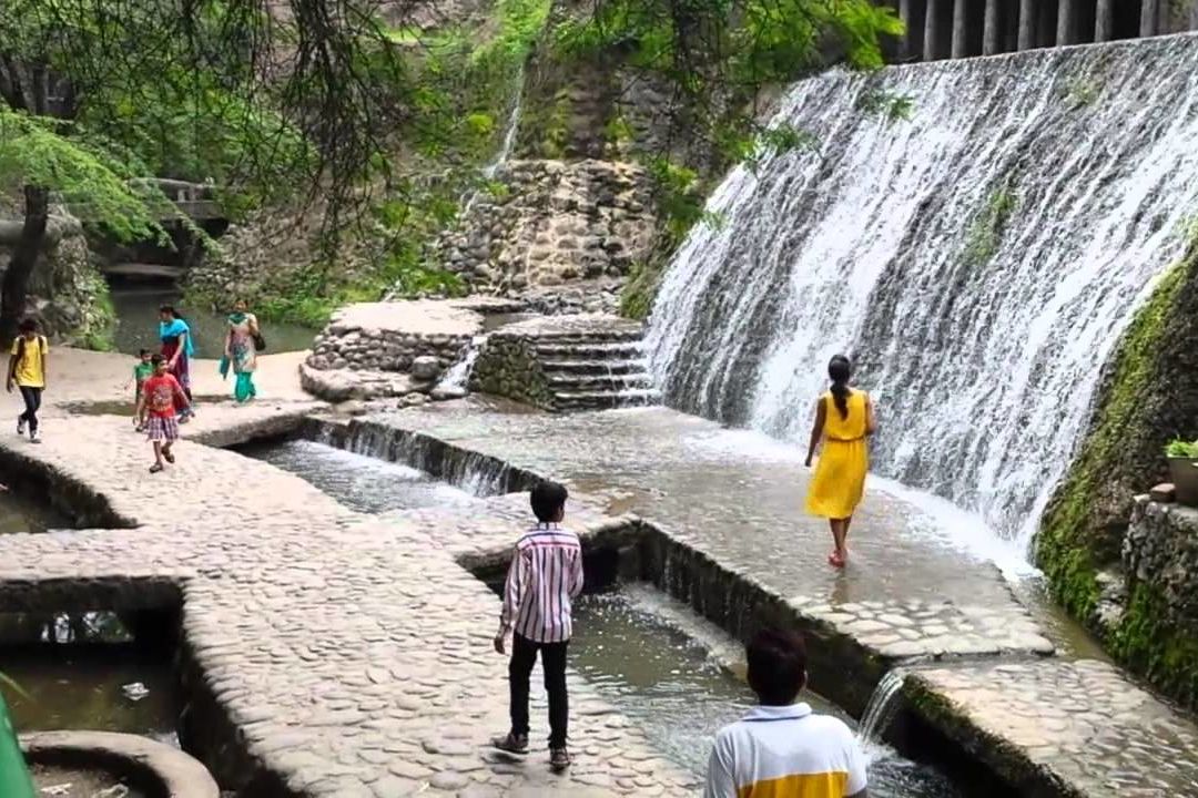 people walking alongside an artificial waterfall at rock garden in chandigarh