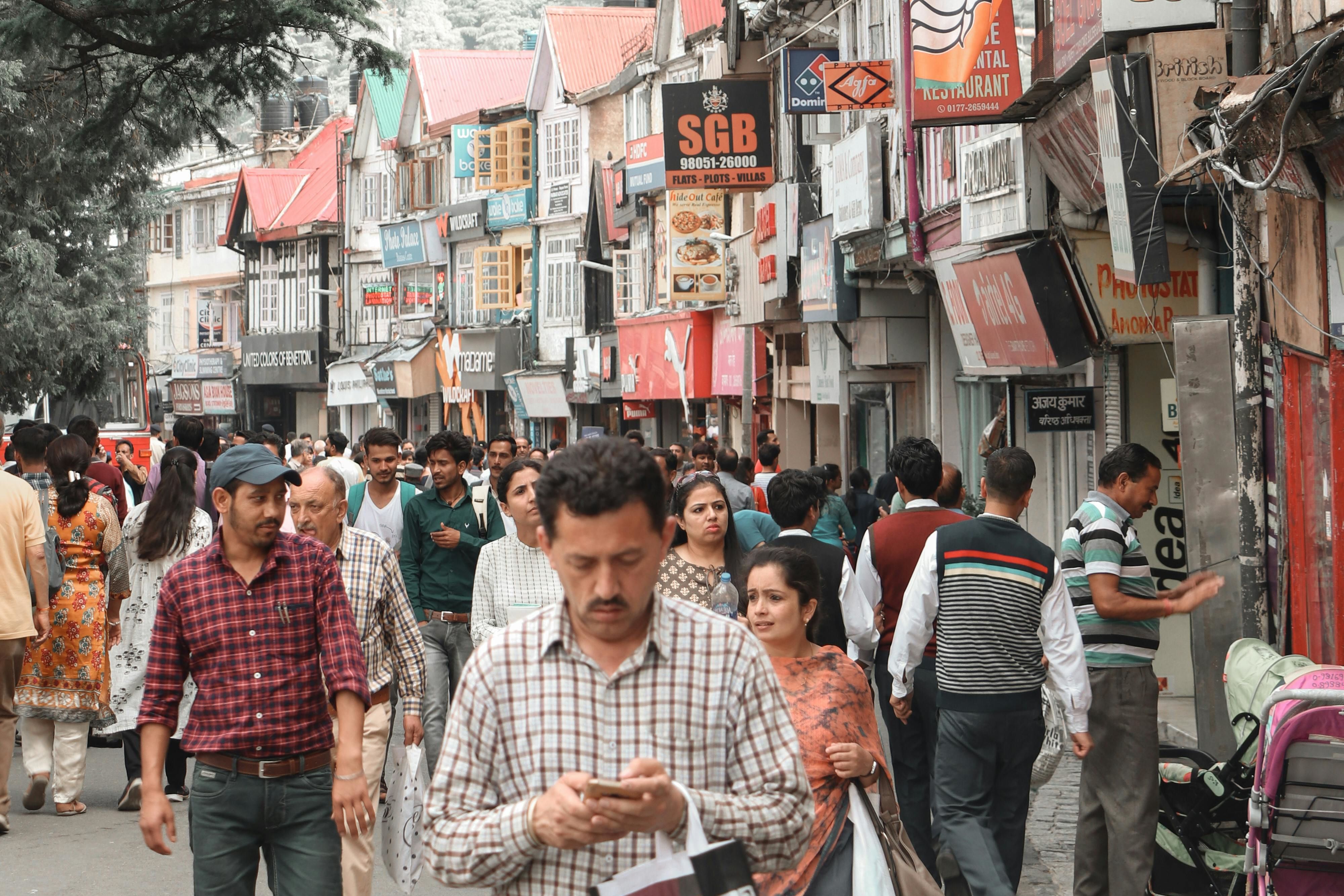people walking on a street in front of shops in shimla