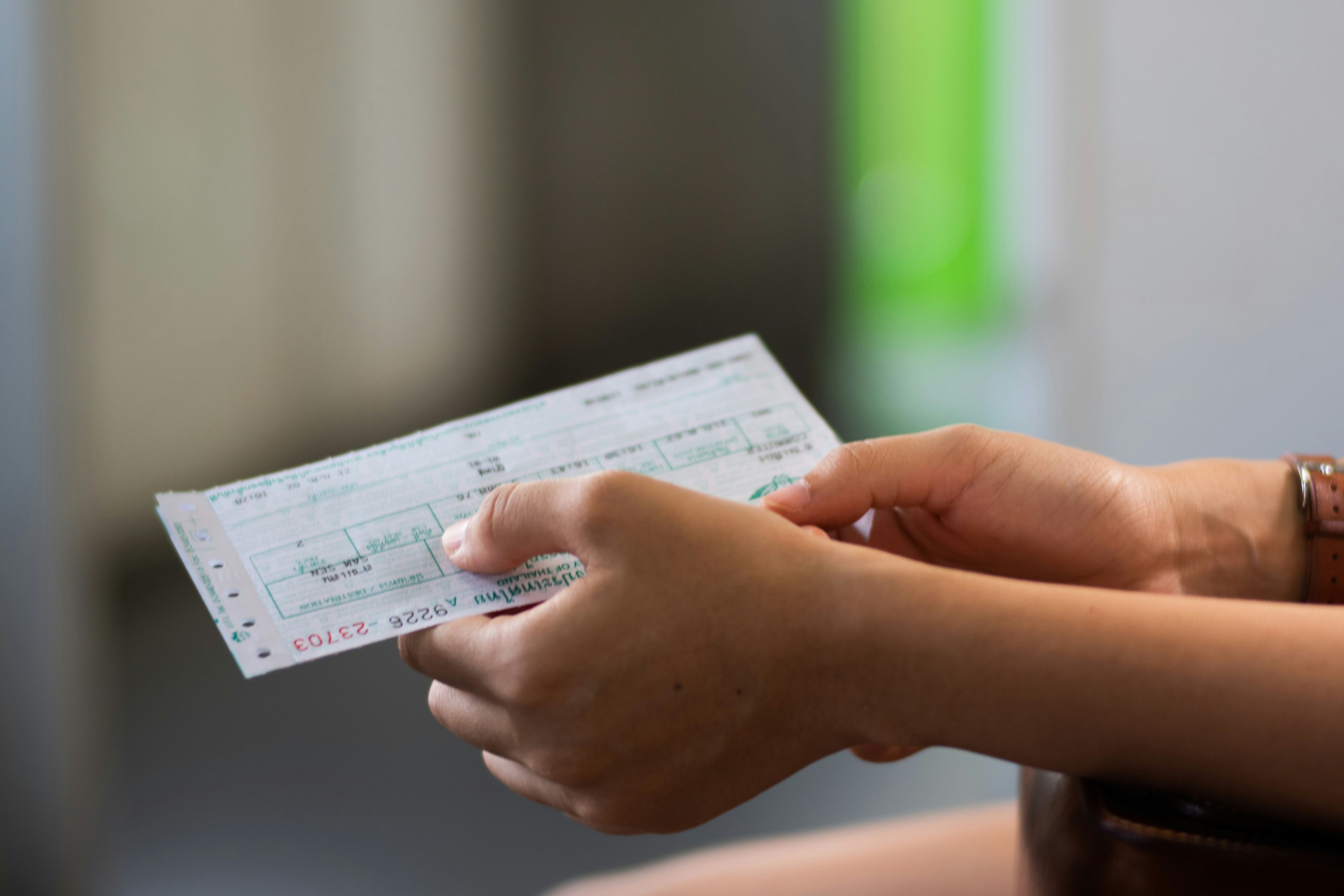 a person holding white paper ticket