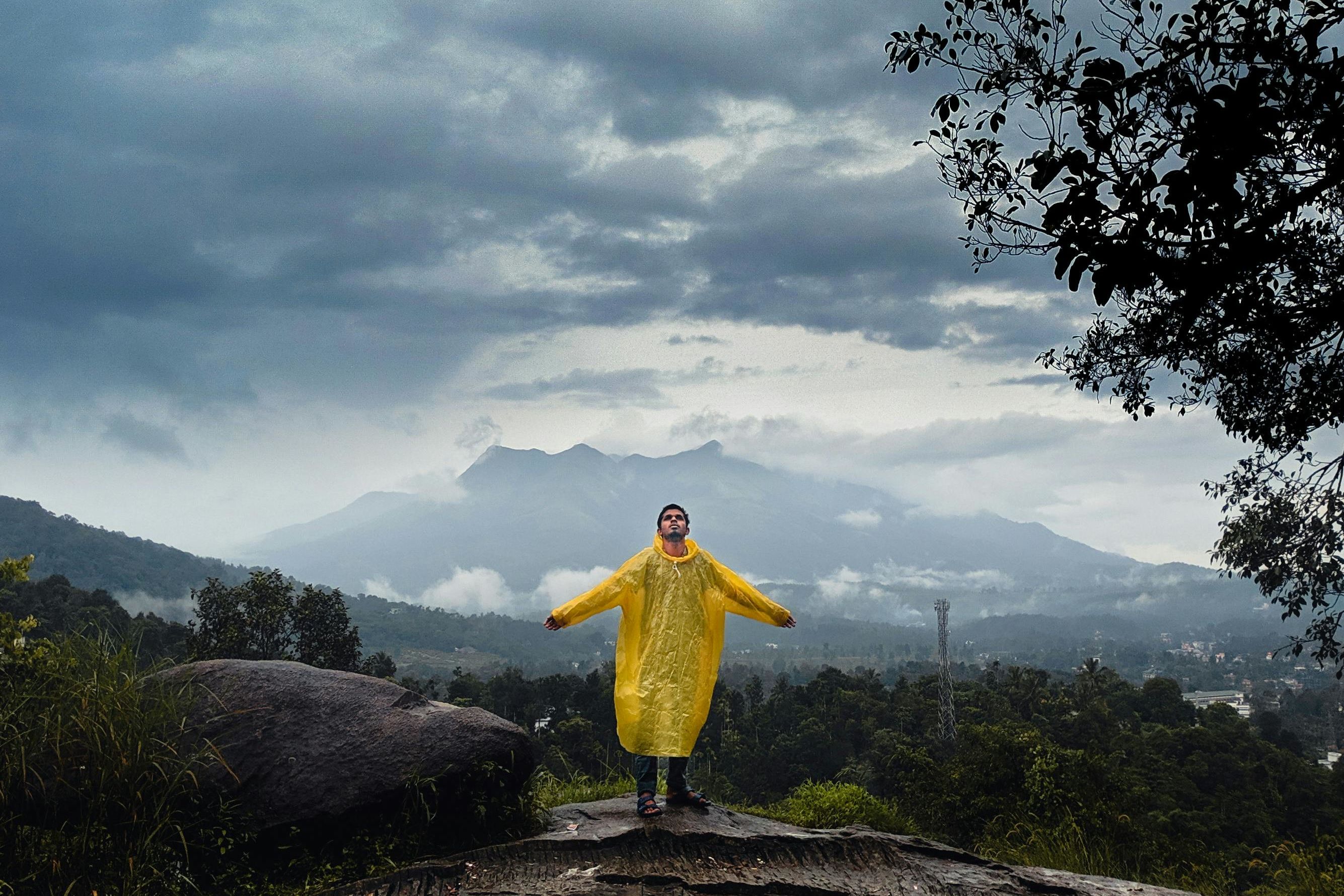 a person in yellow coat standing on top of a hill