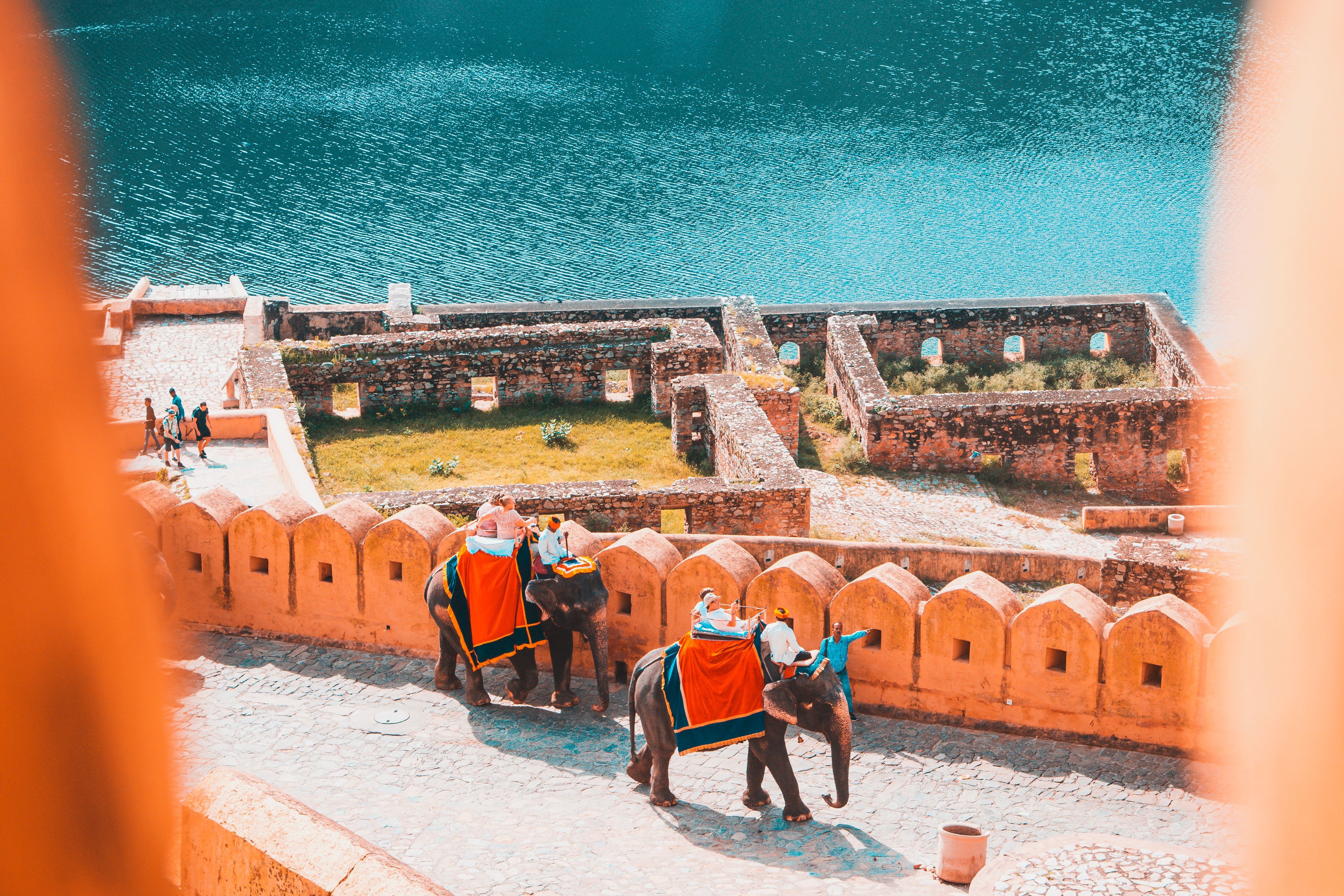 scenic view of tourists riding elephants at amber fort with lake and greenary in jaipur rajasthan