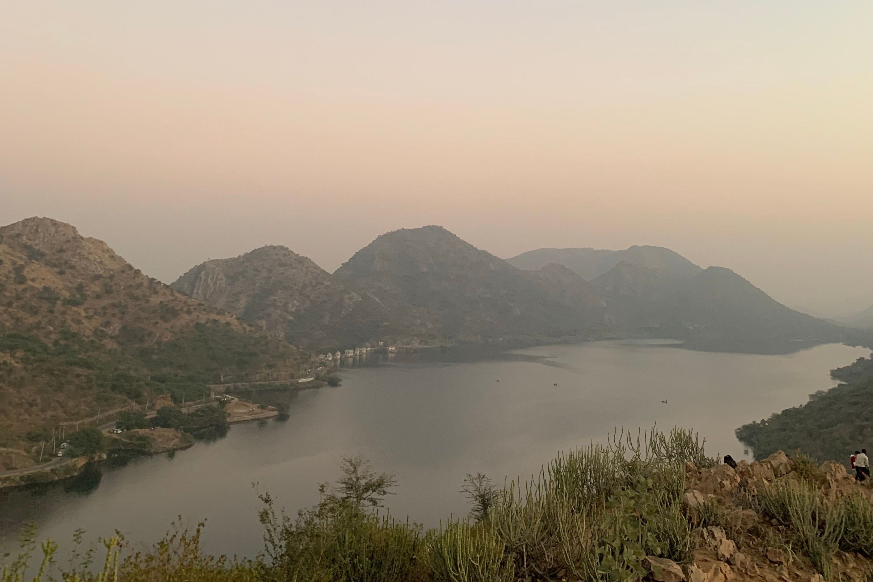 a serene landscape of a tranquil lake surrounded by hills in udaipur at dusk